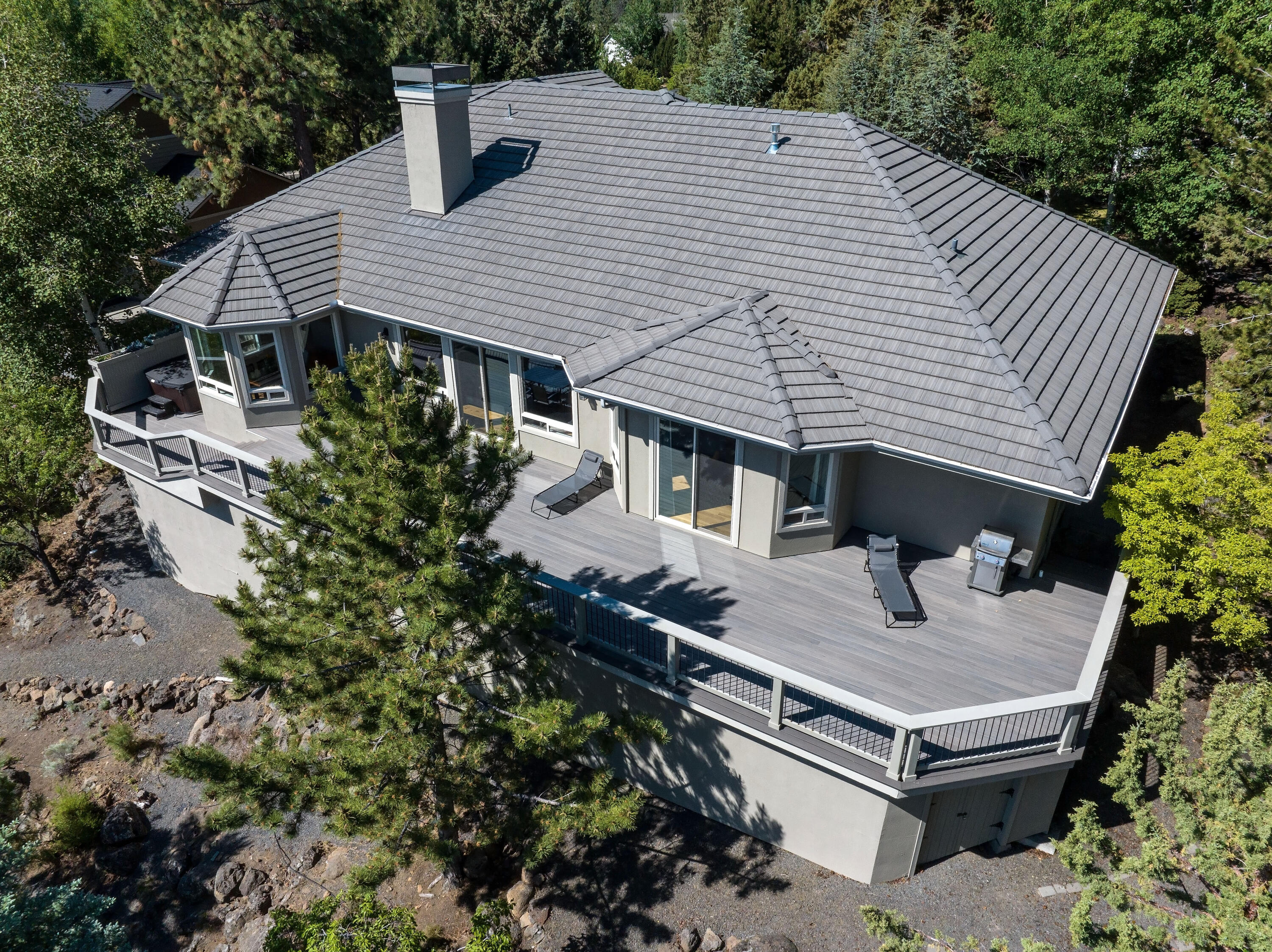 This impressive home in Awbrey Butte presents stunning easterly views of Bend, Pilot Butte & Smith Rock. Enjoy breathtaking Central Oregon sunrises from the large deck, which overlooks a beautifully terraced yard, garden area, and native landscaping. The gourmet chef's kitchen features white cabinetry, a spacious gray island topped with luxurious leathered quartzite countertops, and hardwood floors, with a corner sink that fills the space with natural light. The vaulted great room boasts a double-sided full rock fireplace, formal dining area, cozy breakfast nook, and a wet bar, creating an ideal setting for entertaining. On the main level, the primary suite features hardwood floors, a beautifully remodeled bath, and generous walk-in closet. There are three additional guest rooms on this level, along with an expansive upstairs suite that includes a full bath for friends and family. With ample storage, flat driveway, and an epoxy-floored three-car garage, this home is truly a must see!