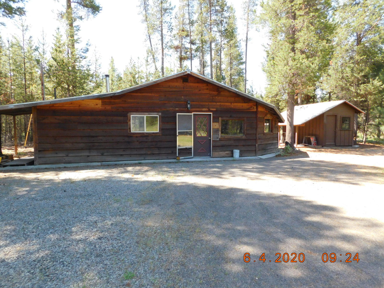 Looking for that perfect cabin in the woods? Here is a rustic style cabin w/ 3 bdrms & 1 bath w/ a formal dining that could also make a great office. There are 2 beams along the vaulted ceiling & no hallways, so this home feels quite large. Seller has updated all the flooring w/wood & 12-inch tiles. Newer cabinets w/new tiled countertops in kitchen & on bathroom cabinet, tile surrounding the shower/tub unit &  is fully plumbed for washer & dryer unit. This home really needs someone to love & finish it. A lot has been done, but not all the finish work. Is in a great rural neighborhood w/low traffic on an acre w/private septic & well. There is a slab already poured & ready for a new garage. The pumphouse has extra storage, a small shop area & a covered area off the side. The back door opens on to a concrete pad & covered firewood area. Circular driveway w/lots of room for a shop, barn or whatever your needs are. The back of property borders private forest land. Sold AS IS
