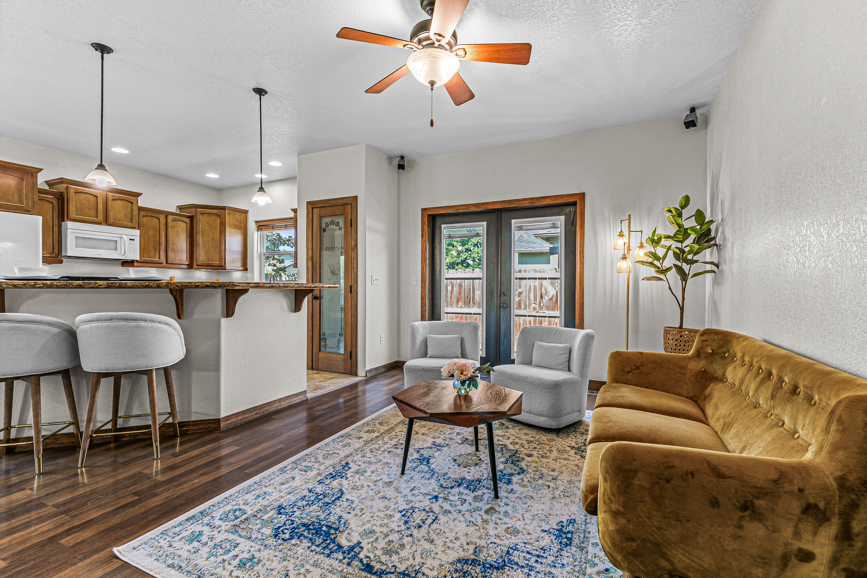 Spacious four-bedroom home in a quiet, inviting neighborhood! From the charming covered front porch to the soaring ceilings, this home is the perfect marriage of cozy warmth and room to relax. The open-concept living room, dining room, and kitchen seamlessly blend function and style with ample cabinet and counter space, a lighted pantry, and a large breakfast bar. The generous primary bedroom is conveniently located on the main level, with private patio access and a well-appointed ensuite bathroom and walk-in closet. Two guest bedrooms upstairs with a full bathroom ensure privacy for family and guests, with a fourth bedroom downstairs that can double as an office or bonus space. The large back patio and manicured, low-maintenance yard create the ideal space for comfortable outdoor living without requiring excessive upkeep, while extra storage and a workbench in the garage provide space for projects and hobbies.