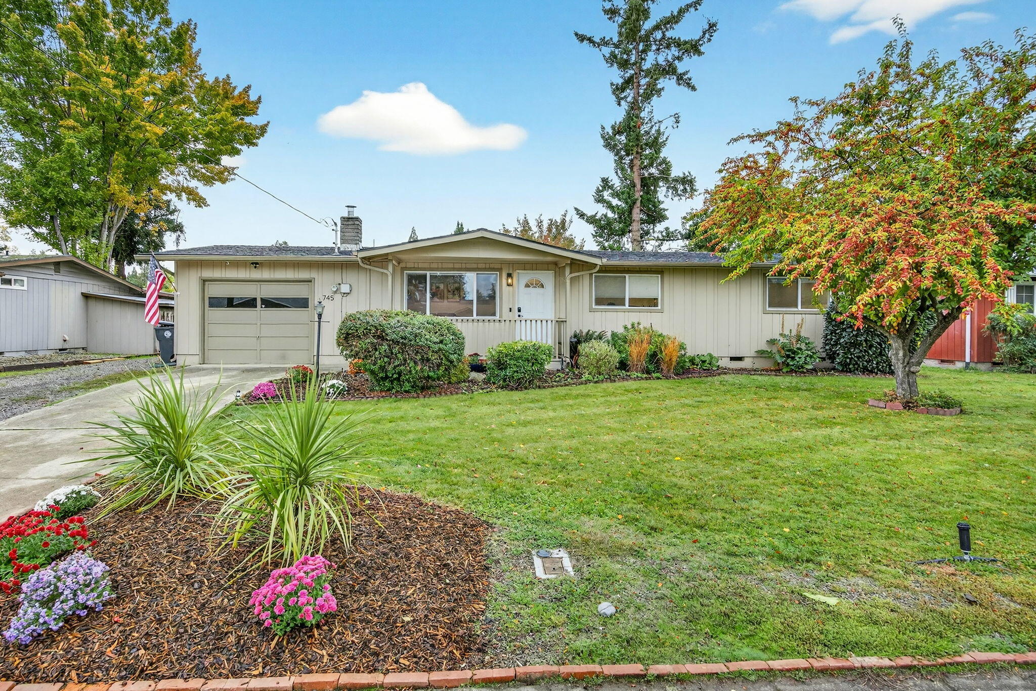 Enter into this beautifully maintained single-level home, where comfort and functionality meet. The spacious living room features a cozy wood-burning fireplace, built-in speakers, picture windows, and durable vinyl luxury flooring. The light-filled galley kitchen boasts tile flooring, a newer range/oven, and seamless access to the adjacent dining area, which opens through sliding doors to an oversized backyard oasis. The remodeled bathroom offers a fresh, modern feel with a newer tub/shower insert, updated vanity, and fresh paint. Additional highlights include a heated single-car attached garage, RV parking with electrical hookups, and two large, detached sheds for extra storage or workspace. The fully fenced backyard is a gardener's dream, complete with a concrete-covered patio, above-ground sprinklers, fresh bark, and ample space to grow and gather.