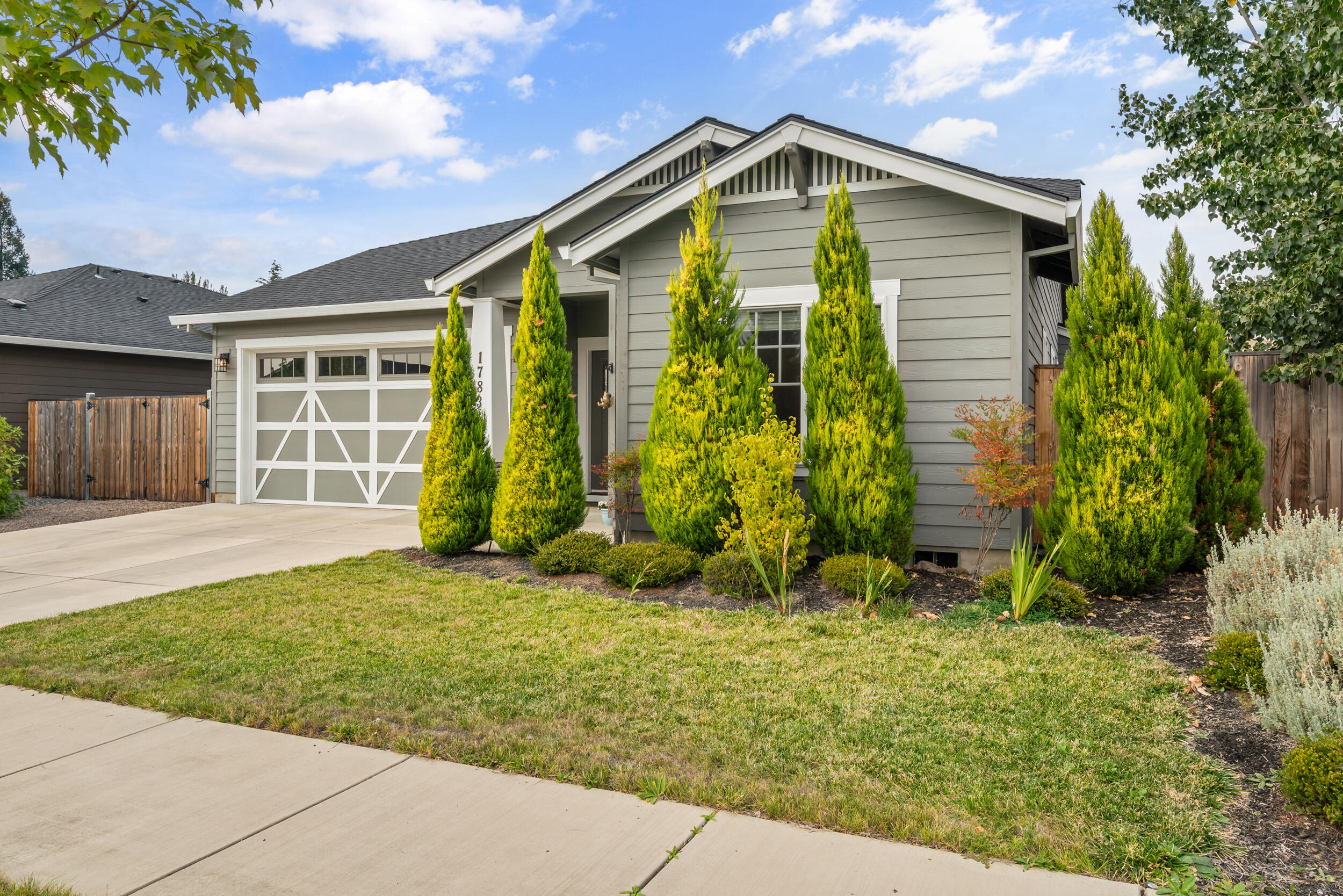 Stunning 3-Bedroom, 2-Bath Home in Northeast Medford. Built in 2019, this single-level home offers modern finishes and a spacious open floor plan. Vaulted ceilings and abundant natural light create an expansive feel. Luxury vinyl plank flooring flows throughout the main living areas. A cozy gas fireplace in the family room, seamlessly connected to the kitchen and dining area. A chef's delight in the kitchen featuring granite countertops, a large island with seating, stainless steel appliances (refrigerator, range, dishwasher, microwave), and ample cabinetry. The large primary bedroom boasts vaulted ceilings and an ensuite bathroom with a dual vanity, granite counters, tile flooring. Dedicated laundry room for convenience. Fenced backyard with patio and garden beds perfect for outdoor relaxation. Situated in a quiet neighborhood, close to amenities.