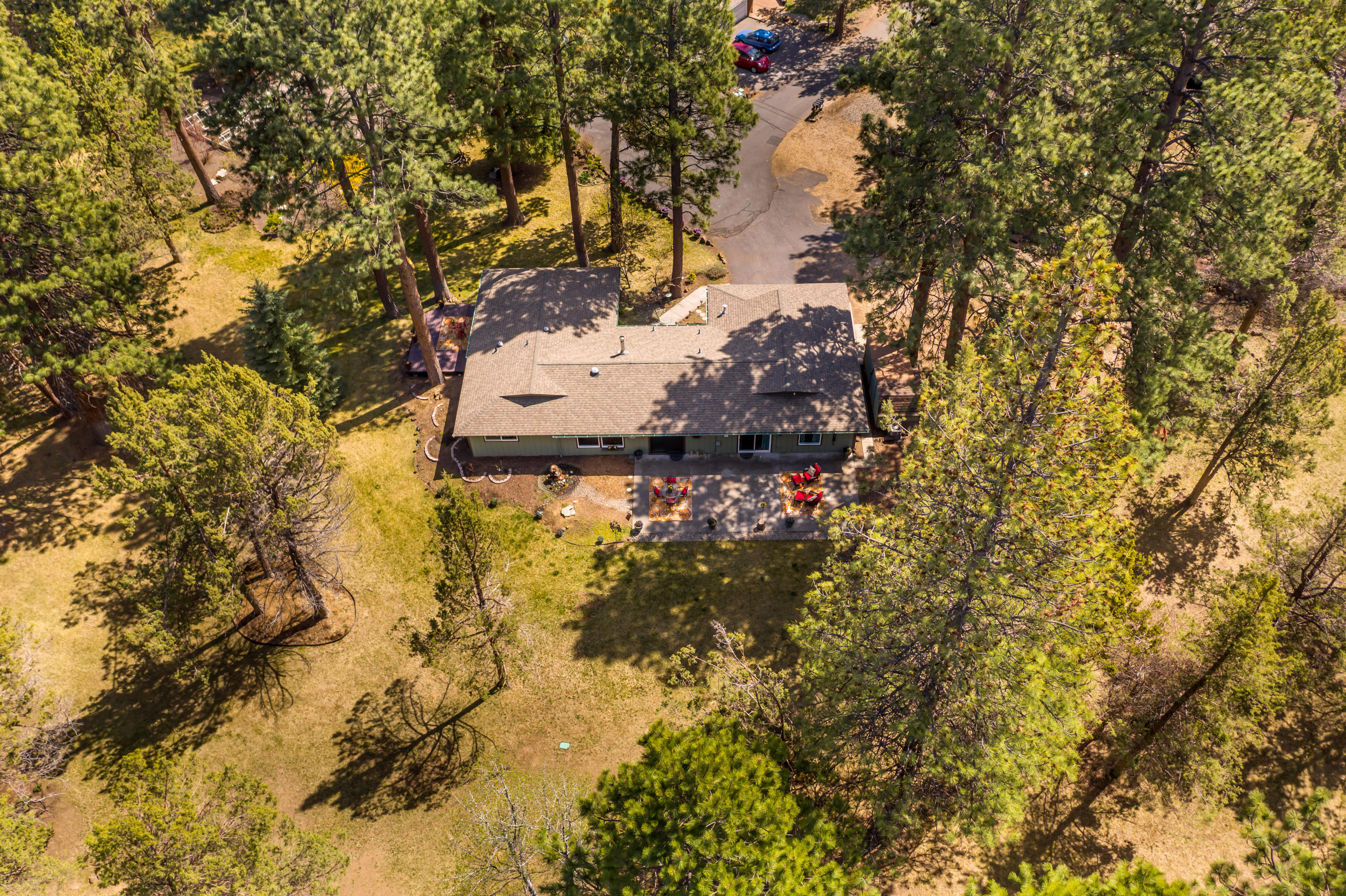 Location Location Location....This beautiful Ranch style home on peaceful cul-de-sac is close to conveniences yet feels like you're living in a park w/ its majestic ponderosas and surrounding common space.  Do you RV? There's ample room for a large RV & toys. Work from home? The office is separated from the 3 Bedrooms just off the  family room. Primary bedroom opens to a deck perfect for morning coffees. Nearly every window takes in views of greenery. Certified Jodel woodstove provides cozy winter ambiance yet there is still the 2018 Forced Air Furnace w/ PureAir HEPA air purifier & new A/C unit – every season covered!  There's more! Solid surface counter, ample kitchen/dining area built-ins, SS refrigerator, Washer, Dryer, & TV. Two sliding doors exit to large back patio.  It's spacious, flat, perfect for entertaining & backs to 3 acres of beautiful common space maintained by the HOA.  This really is a special place.