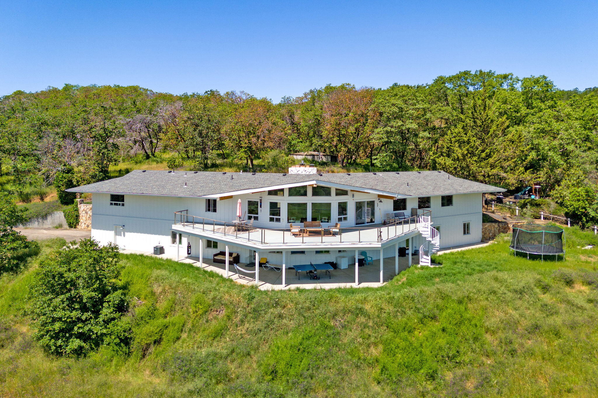 Private estate located in the coveted west hills of southern Oregon; this property offers panoramic views of Rogue Valley. Completely remodeled in 2019, this 6,000+ sf home has two living rooms and a stunning kitchen featuring a 14' granite island and eating bar, equipped w/Wolf 4-burner cooktop with griddle, double ovens, Subzero refrigerator/freezer, butler's pantry, and much more. On 2 levels, with 5 bedrooms, office, bonus rooms, 2 laundry rooms, home theater with five screens and a bar. The primary suite is on the main floor, features a walk-in closet, a huge carrera marble shower w/3 shower heads. The main floor living room has vaulted ceilings with wood beams, flagstone fireplace with gas insert and breathtaking views. This property is entered via a private driveway where one passes by multiple out-buildings: two barns, 3 bdrm/2 bath, 1,782 sf rental property. 2 wells and a 10K gallon holding tank. If you have been looking for something truly special, this is it.