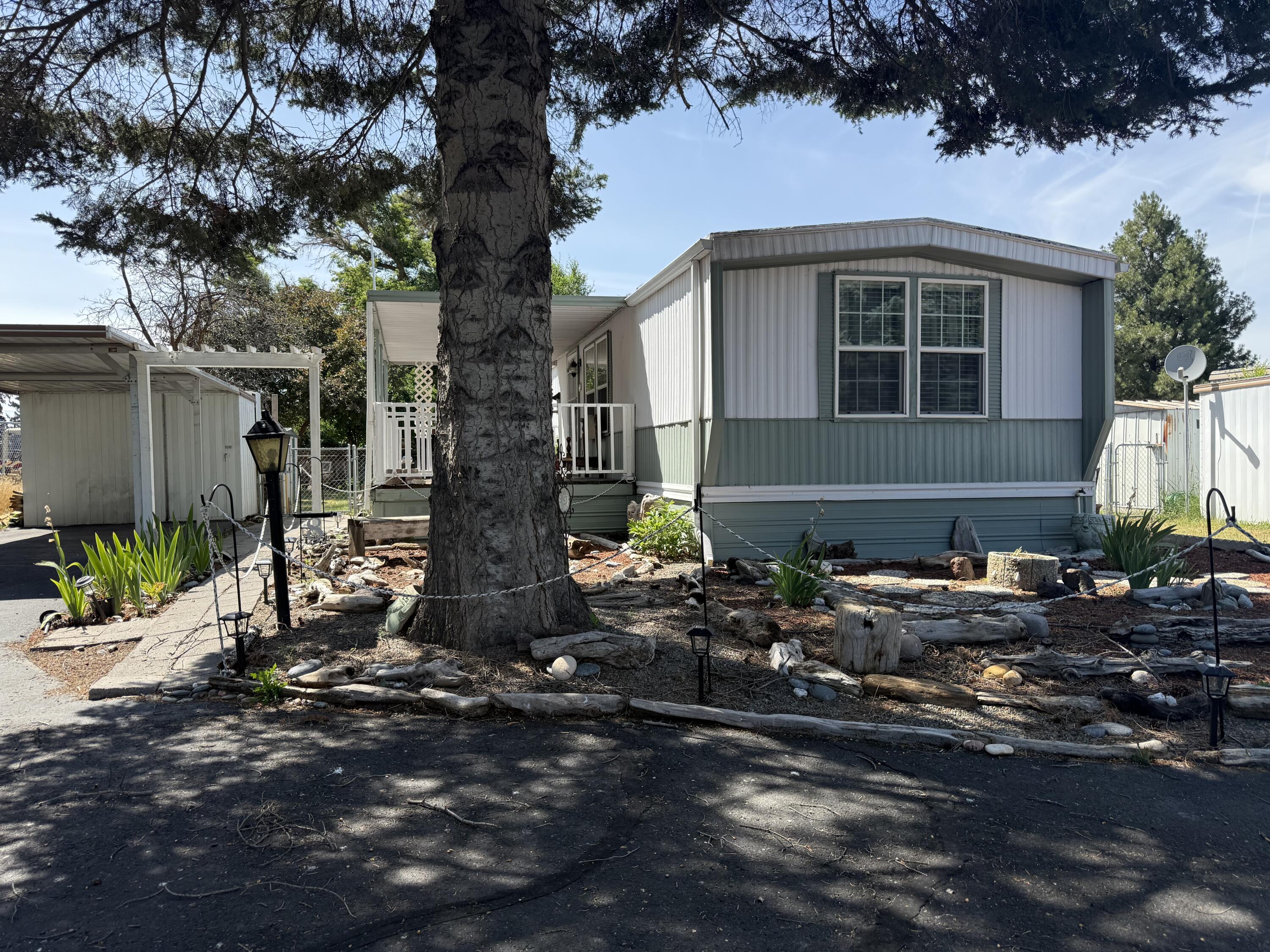 Enjoy the easy living in this 55 & older park, this cozy home is situated at the end of the street on a nice sized lot. The yard is fenced with multiple sheds, carport, garden areas and a covered front porch. Inside the primary bedroom is equipped with its own full bathroom, good sized kitchen and living room, laundry hook-ups and some recent upgrades. The second bedroom and bathroom are spacious and have good closet storage. The monthly rent covers water, sewer, trash. Please submit park approval with any offers.