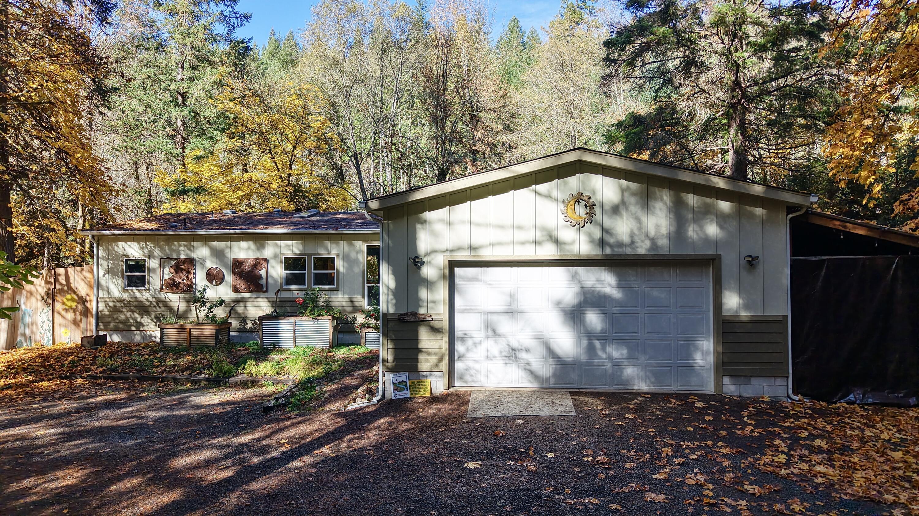 Discover your dream retreat on 10.29 stunning acres with year-round creek frontage with multiple swimming holes spanning the entire lower edge of the property! This 2018-built 3 bed, 2 bath, 1,680 SF home offers an updated modern interior with Pergo barn wood floors throughout & tranquil creek views from the living areas and back deck. Enjoy a fully fenced and gated property providing privacy and security—perfect for animals and country living. Additional features include RV parking with full hookups, an attached 2-car garage, outdoor shower, and expansive flat, usable land ideal for gardening, recreation, or future projects. Marketable timber and open space offer endless opportunities to explore, relax, or expand. Property backs to almost 500 acres of BLM land, giving you direct access to vast wilderness right from your front yard. A rare blend of natural beauty, freedom, and modern comfort—your ideal rural escape awaits!
