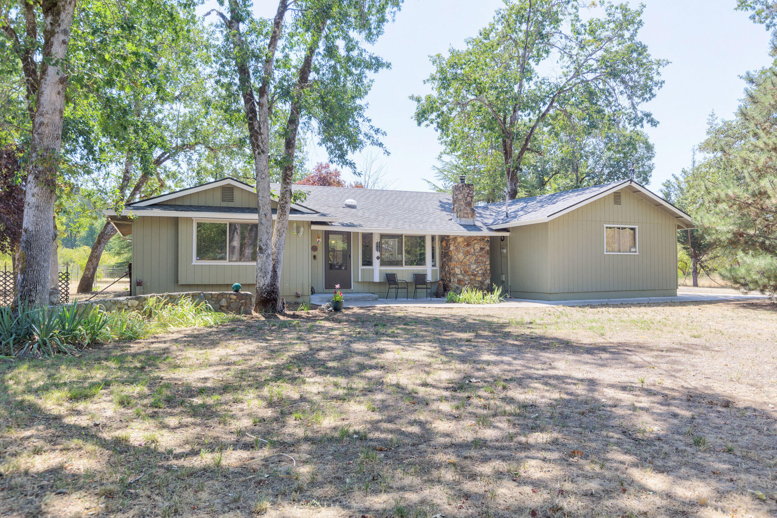 This charming 3BR/2BA Southern Oregon home offers 1,248sqft of comfortable living with beautiful Jump Off Joe Creek frontage and peaceful surroundings. The living room boasts a vaulted ceiling with a striking beam, a rock fireplace with certified insert, and thoughtful updates throughout, including luxury laminate flooring in most of the home. The light, bright kitchen features a brand-new Butcher Block island—perfect for cooking, entertaining, or enjoying your morning coffee. Primary offers en-suite. The open layout feels spacious and inviting. Outside, the level 2.18-acre property provides a fenced garden area, separate storage shed, and dedicated RV/boat carport. Stunning creek frontage offers the perfect spot for relaxing or soaking in the natural beauty right from your own backyard. With room to roam, modern touches, and a serene setting, this property blends comfort and nature beautifully.