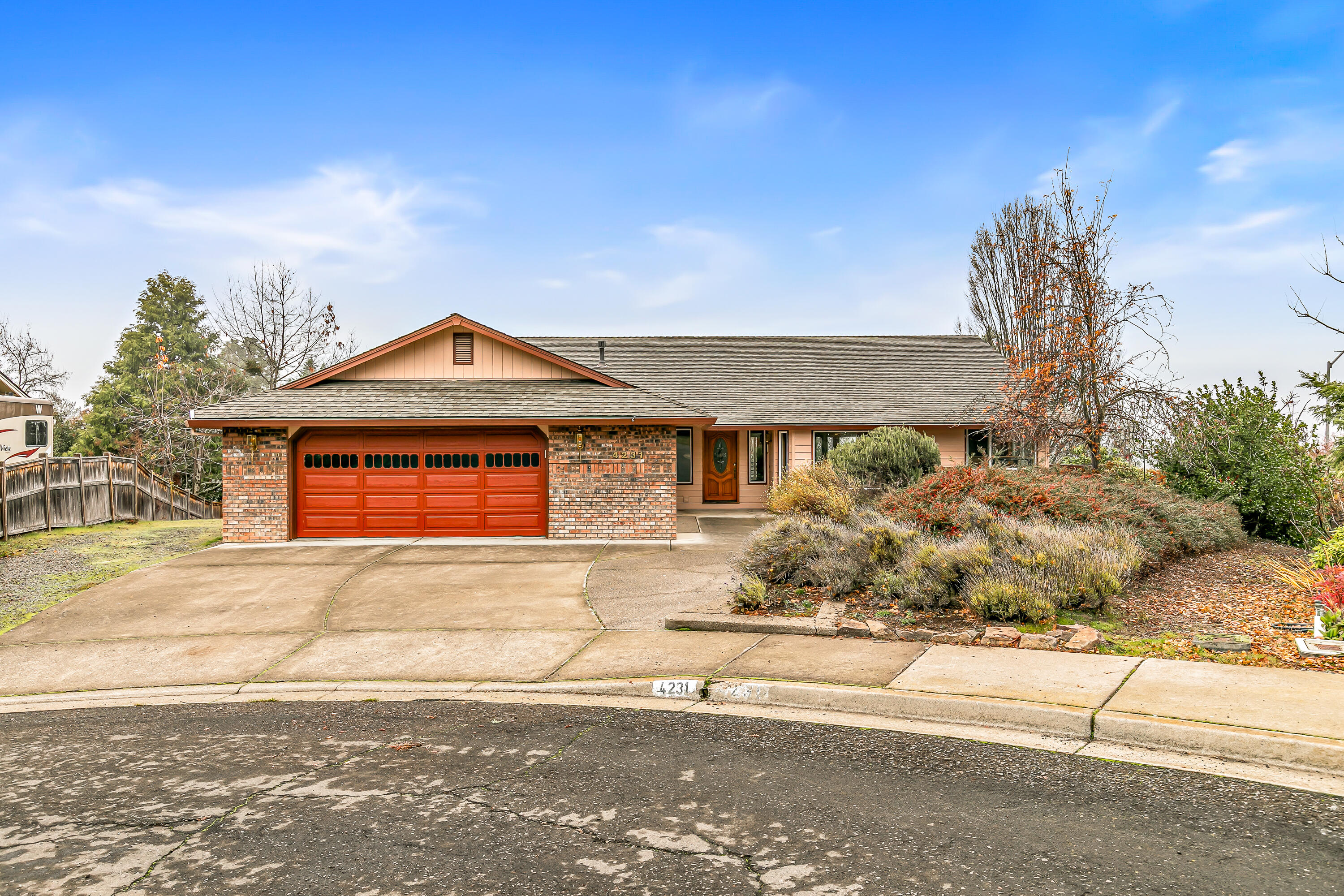 Discover a home with incredible potential in desirable East Medford. This 3-bed, 3-bath residence offers a spacious floorplan, featuring vaulted ceilings, wood flooring in the kitchen and dining area, and a cozy gas fireplace in the living room. Lots of windows and a generous deck capture beautiful views, along with custom wood built-ins throughout the home, offering abundant storage. The lower-level living area features its own private entrance, bathroom, and kitchenette—an excellent setup for multigenerational living, guest quarters, or potential rental income. The oversized 2-car garage provides ample room for vehicles, while the downstairs workshop is a dream space for hobbies. The property also offers room for RV parking, along with established landscaping and tall hedges that create a sense of privacy. Additionally, the vacant, buildable, adjacent lot is available for purchase, presenting a rare opportunity for expansion, investment, or added privacy.