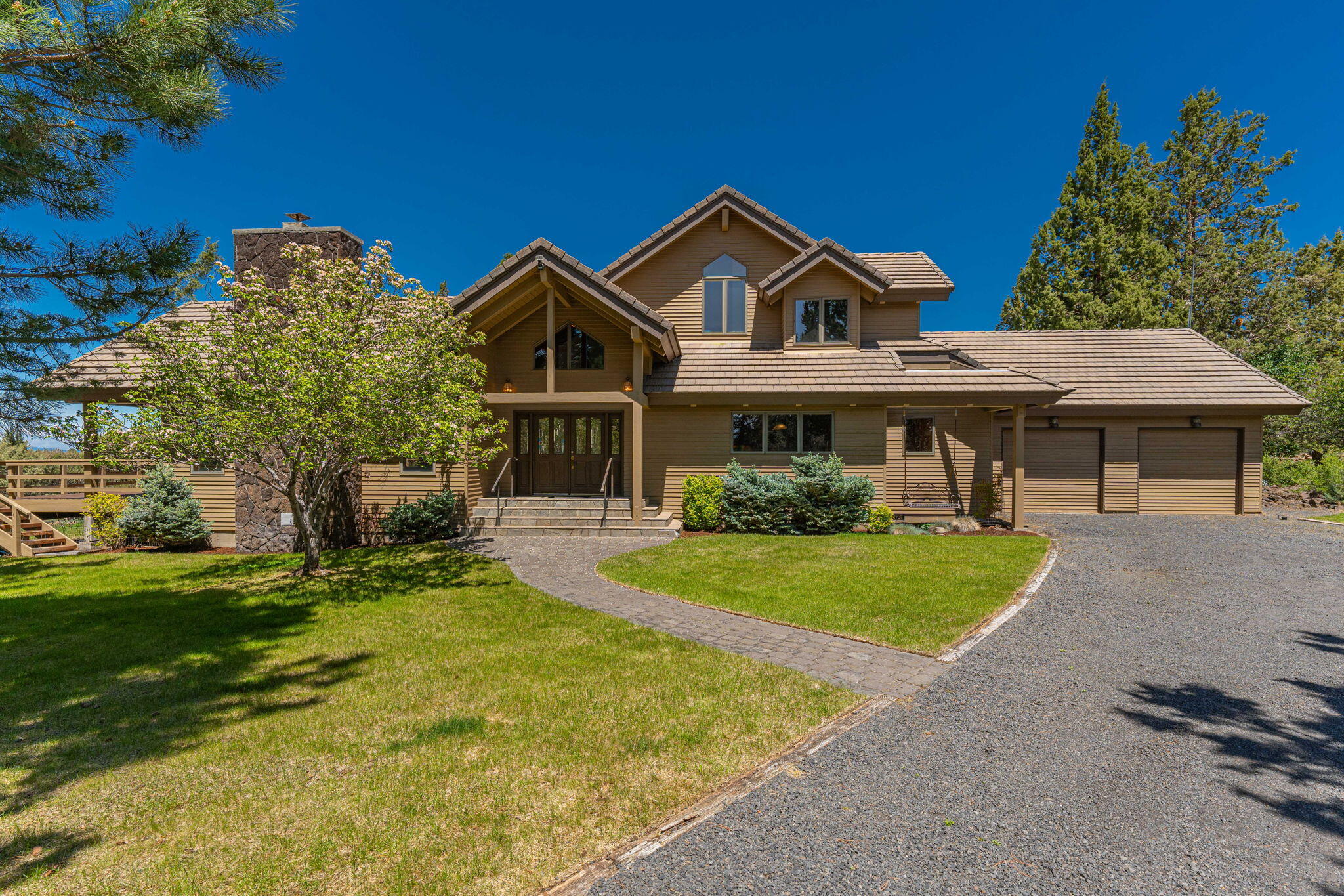 Escape to tranquility in this lodge-style home with vaulted cedar ceilings and a wall of view windows offering a 180-degree panorama of mountains. Step onto the immense deck or relax in the adjoining dining room with built-ins and a wet bar. Perfect for entertaining, with a bonus room for media or office space. The kitchen features a butcher block island, under-counter lighting, and all appliances. The main floor boasts a generous primary ensuite with upgrades like a double vanity, heated tile floor, tile shower, and soaking tub. Upstairs are two bedrooms and a second full bath. Outside, enjoy your swim spa on the deck, an oversized two-car garage with workbench, and a huge three-bay shop with workshop. Plenty of parking on the circular driveway and RV parking available. The 5-acre lot, with a generous lawn area, offers peaceful privacy in a quiet neighborhood very close to Bend.