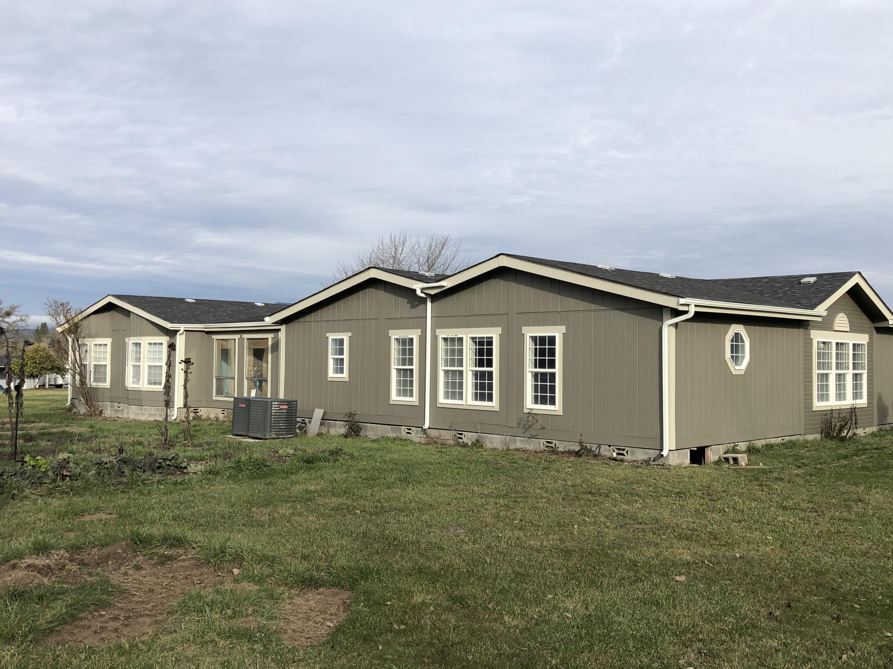 Very unique 2 family set-up.  2 manufactured homes (a 2238sqft triple wide and a 1782sqft double wide) extensively remodeled and attached with a large (864sqft) bonus rec room. The triple wide has new paint, new flooring, painted kitchen cabinets, with island and eating bar, family room, dining room and living room. Very open and spacious, the master is very large with 2 walk-in closets, master bath has a soaking tub and two sinks. The second is a 1993 double wide that has 3 bedrooms, 2 baths that includes the bonus rec room.  There's a 2 car 2-sided carport with storage, a 4-stall barn for horses or animals, the land is level and irrigated with a training area. Corner property with 2 access driveways.
