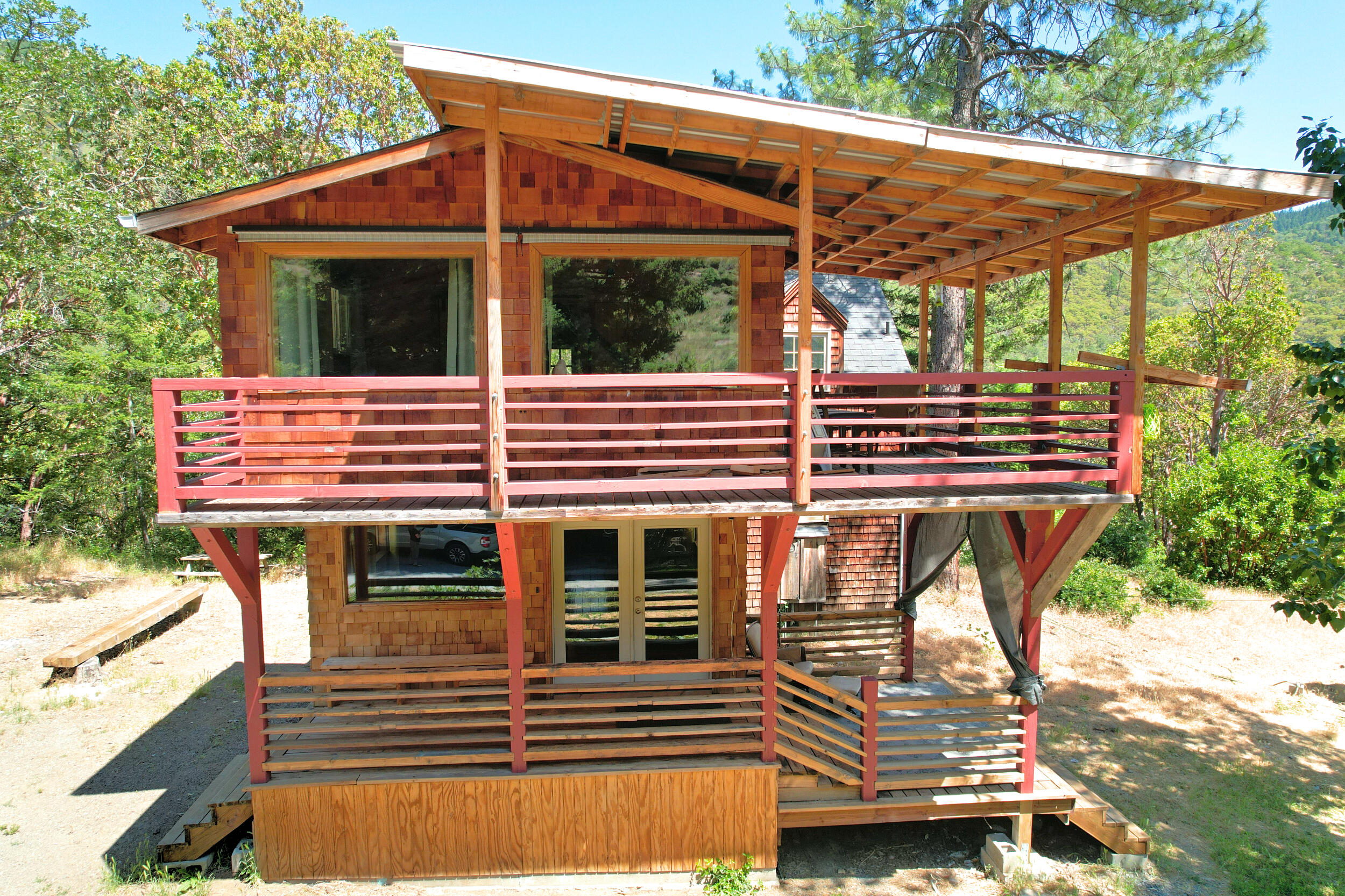 Charming Mini-Farm on Humbug Creek in the Applegate Valley. Cross a creek through the forest up to your own private little hobby farm homestead on 11.2 acres backed by 4,900 acres BLM. Unique, cozy custom built cedar sided home with dramatic architectural angles, custom details & rustic charm. Central wood stove, vaulted ceilings, stone & bamboo flooring throughout. Detached laundry room with additional storage & covered firewood area. Turn-key fenced & terraced garden area sports 3 automated greenhouses (one solar), mature fruit trees, blueberries, animal corrals & a chicken coop. Spacious workshop w/ vaulted ceiling is set up for wood stove, a previously certified kitchen & view into the attached hothouse. Hike up the hill to gorgeous views. A dreamy must see!