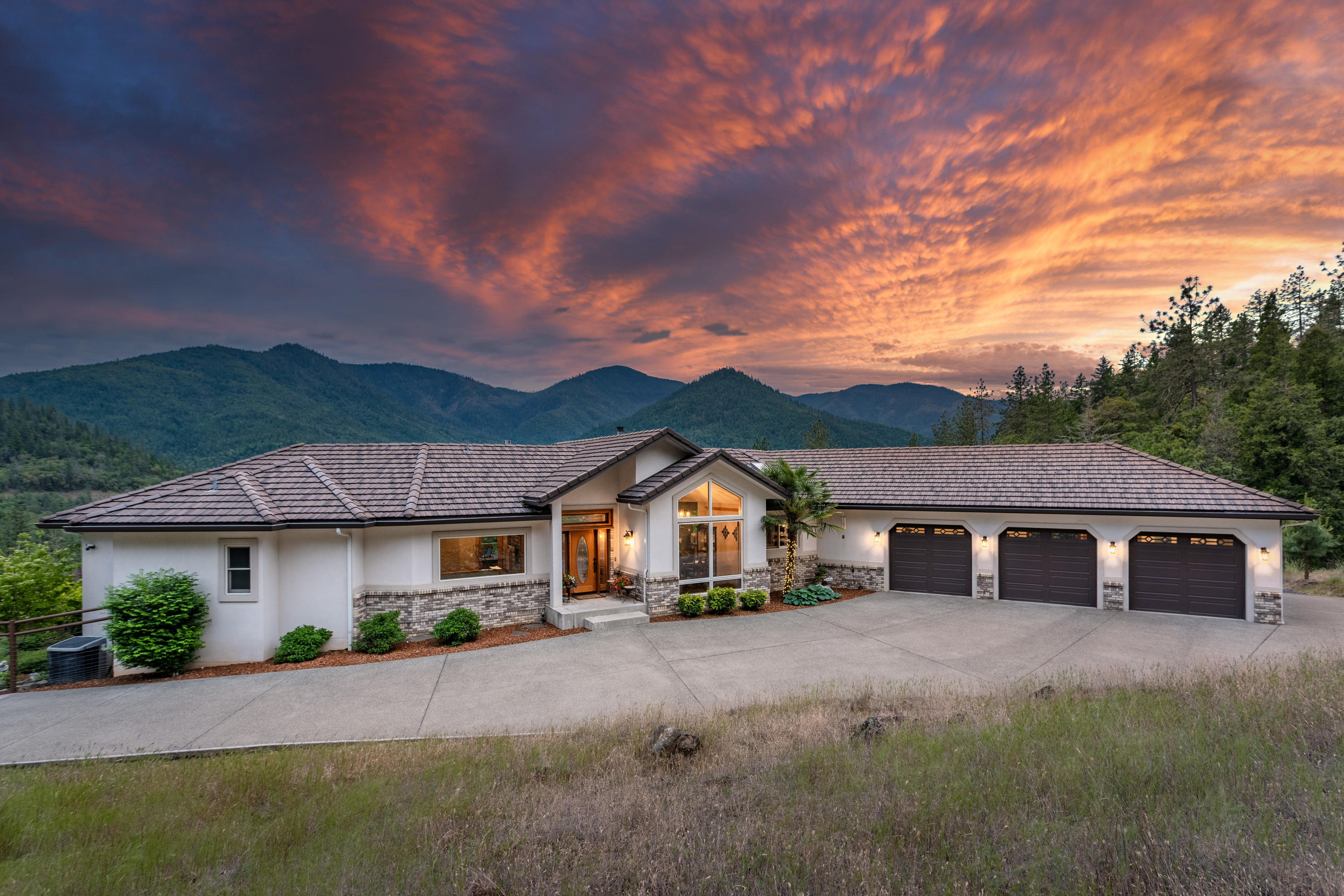 Located minutes from town & the Applegate River, this custom home on 20+ acres, backed by hundreds of acres of BLM, is distinguished by the rare combination of seclusion & convenience.  Built in 2002, this 4576sf residence boasts breath-taking views from every room, large light filled windows & natural wood accents. Spacious main floor includes family room, home office, dining room, half bath & open great room complete w/ well-appointed Kitchen, large pantry & glass doors that lead to the expansive deck overlooking the mountains, plus the main floor Master includes a private deck & spa-like ensuite bath ensuring homeowners a private place to relax. Having guests? You'll love the lower level complete w/ 2 guest rooms, bathroom, bonus room w/ wet bar, plus a theater/game room, 14X23ft workshop & 2 storage rooms! Outside you'll find a fenced yard w/ lush landscaping & water feature plus a paved driveway w/ security gate, 3 car garage, RV parking & more! Ask for the Video & Virtual Tour!