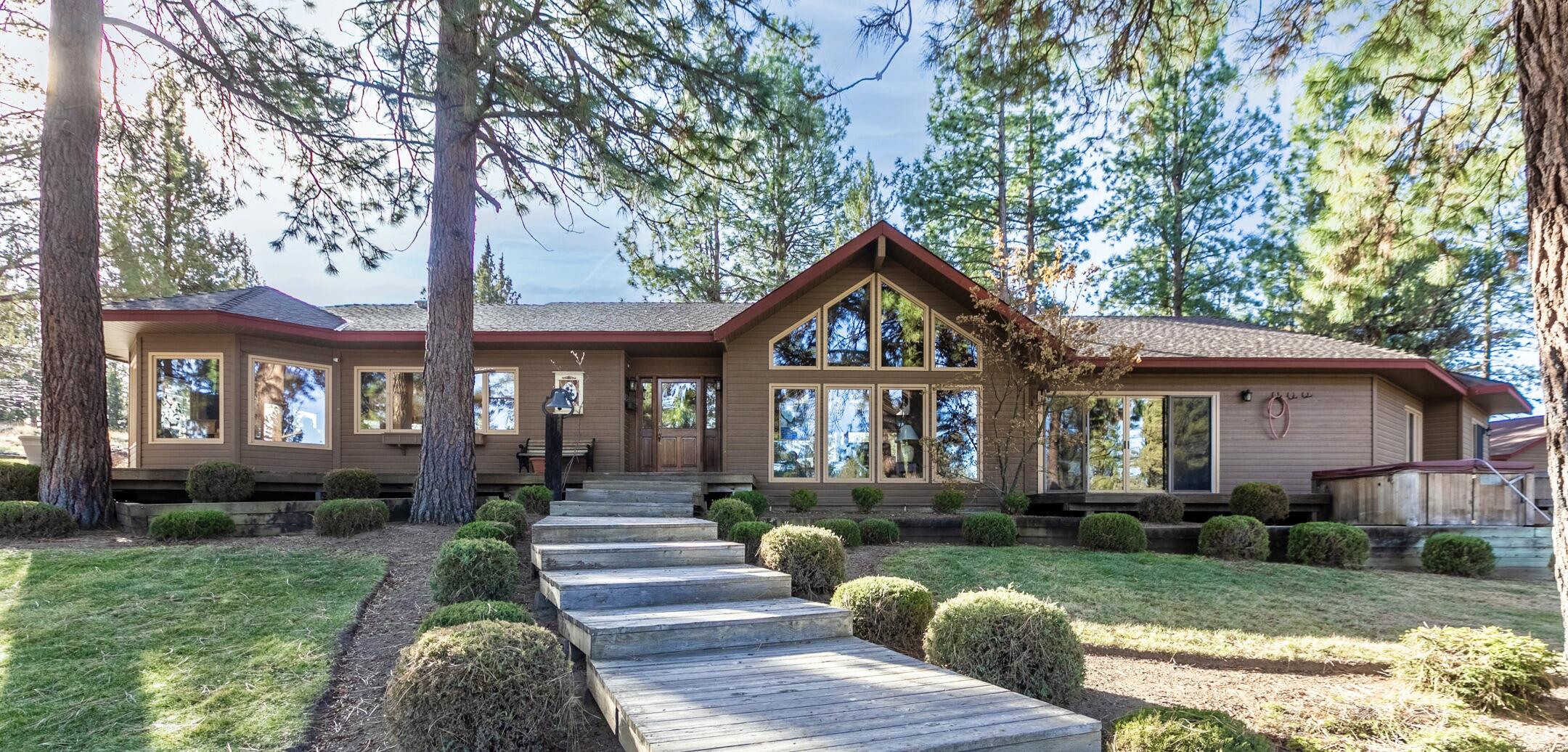 Come home to 20 acres of peace & privacy, yet minutes to town! You cannot see a single neighbor from your immaculate & beautifully updated single-level retreat in the pines! Relax on decks& patios or gaze from the many large windows flooding your home with natural light. Gourmet kitchen, huge dining space and great room feature natural wood ceilings, beams, vaults & windows on all sides to sync with the natural rhythm of the forest & seasons. Separation of 3 light filled bedrooms and 3 full bathrooms. Also find a separate office or TV room. Home includes many built-ins and storage & beautiful gas fireplace. Kitchen & bathrooms all updated, newer furnace, heat pump & water heater. PLUS! Sep 3000 sf garage/RV/rec storage with GUEST QUARTERS & huge craft room. A 2nd barn/garage and covered parking area or hay storage. The full 20ac is fenced and the pastures & pond are almost completely cross-fenced with underground irrigation. This property can easily accommodate animals. Full RV hookups