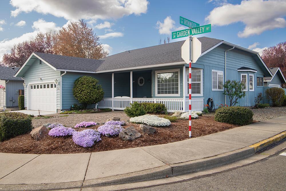 Charming 3-bed, 2-bath home on a desirable corner lot in a great Grants Pass neighborhood! This 1,306 sq ft gem offers vaulted ceilings, bay windows, and skylights that fill the space with natural light. Enjoy a spacious living area, a comfortable layout including a breakfast bar, The large covered front porch with a picket fence rail and the covered back patio make outdoor living easy year-round. The low-maintenance yard, and a 2-car garage add convenience and peace of mind. Just minutes from Reinhart Park, the Rogue River, and downtown. Location and lifestyle combine perfectly in this home! Come see it today.