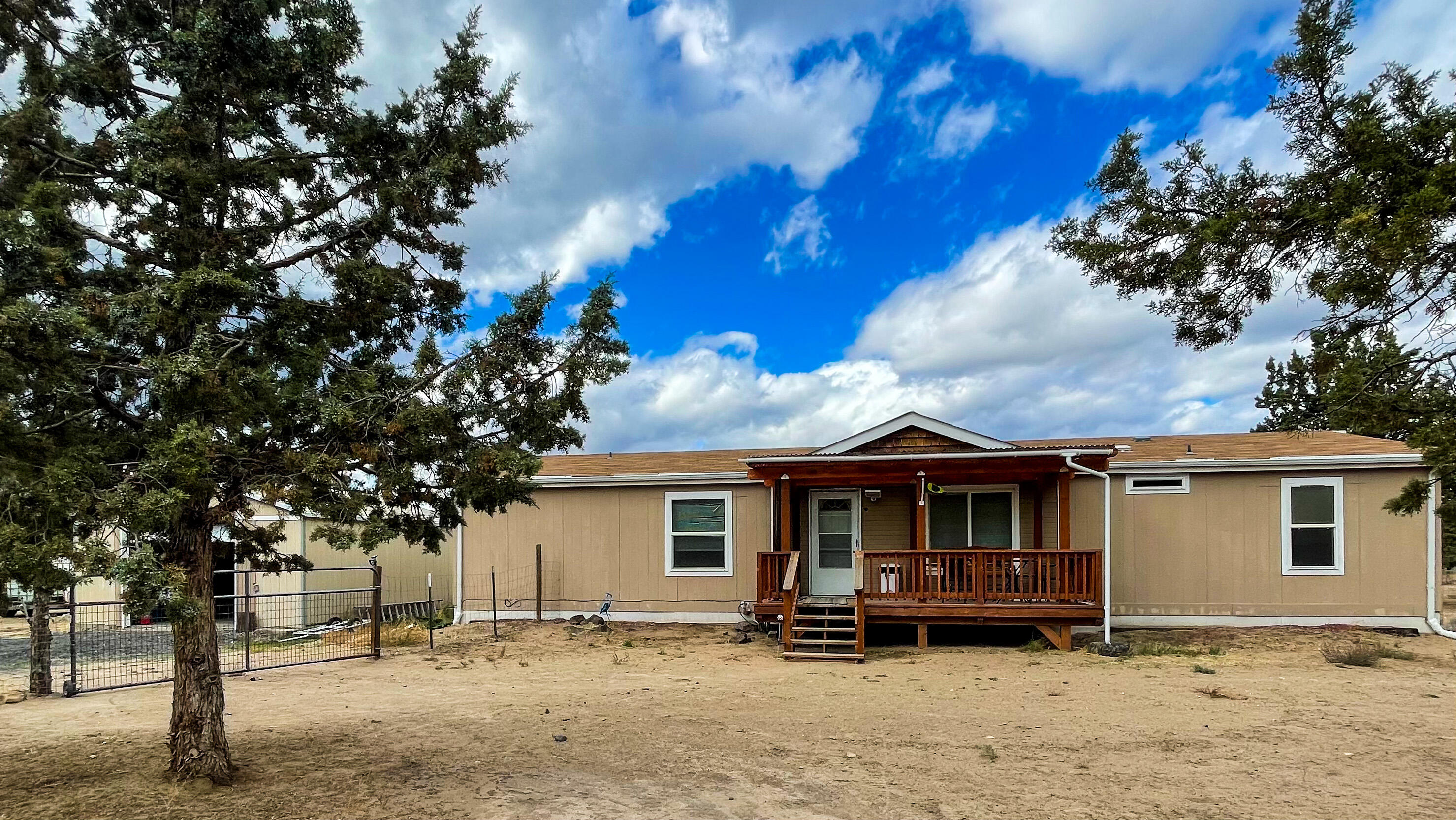 Secluded acreage and home ready for all your recreational dreams! Hard to find 4 bedroom, 2 bath manufactured home with a separate garage equipped with garage door opener and concrete pad. Spacious open floor plan with master separate from bedrooms. Fourth bedroom can be used as an office/den. Tons of counter and cupboard space in the bright kitchen. Enjoy the outdoors on either the front or back deck. Hay barn out back for animal shelter or store your toys. Property has a garden shed and chicken coop as well. Property is completely fenced with an additional fenced front yard.