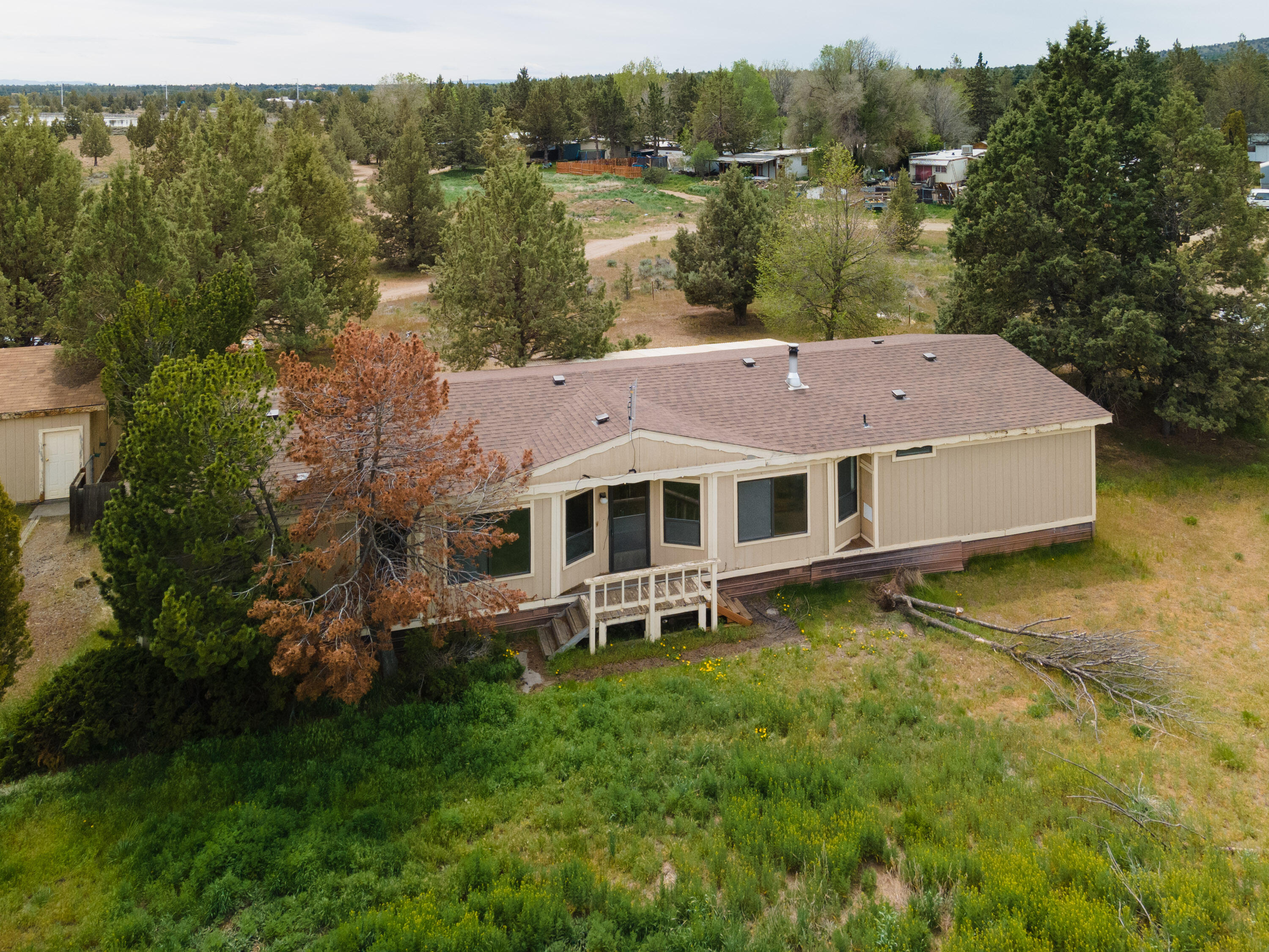Opportunities abound at this 2.14 acre property on a private airstrip located right across the highway from Eagle Crest in beautiful Redmond, OR! Fly directly into town and park in the 1600 sq. ft. hangar located at the end of the runway. The 1983 manufactured home and it's 1782 sq. ft. floorplan is functional and spacious. With a separation between the guest bedrooms and the primary, it offers privacy, beaming natural light and a ton of open space. The large open kitchen has plenty of storage and comes complete with a fridge (washer and dryer are also included). Home has central heat and air, along with a woodstove. In addition to the huge hangar, there is also a 2 car detached garage giving you ample parking and/or storage. Live in the home or build your own dream house.