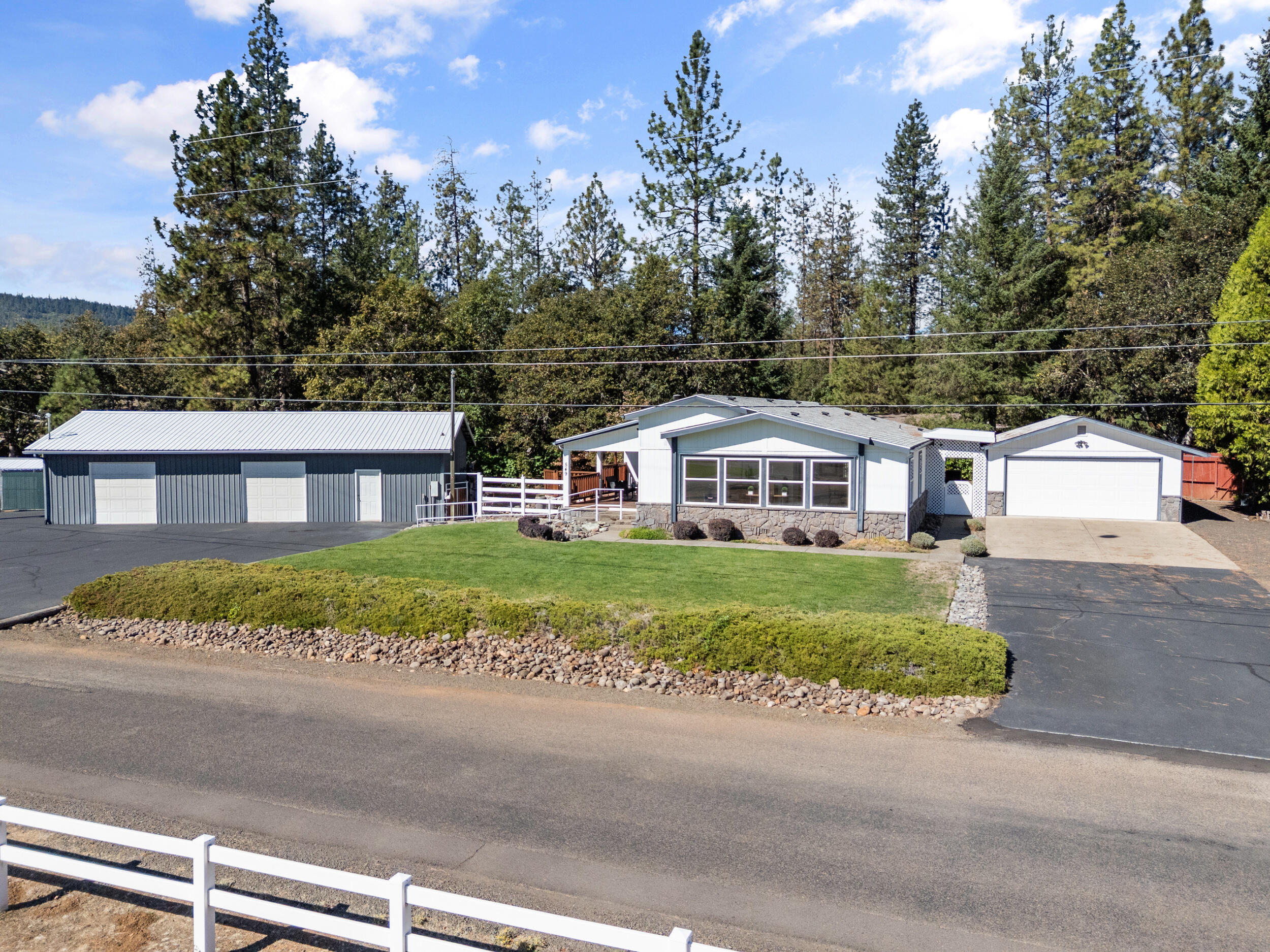 Located in the highly sought-after Shady Cove Airport Division, this meticulously maintained home is filled with natural light and charm. Featuring vaulted ceilings throughout, the spacious layout includes a beautiful formal living room, a large dining area for entertaining, and a second living room/den with a cozy fireplace. The huge kitchen boasts stainless steel appliances, ample cabinetry with custom pull-out shelving, and abundant storage. The generous primary suite offers a large walk-in closet and private bath. Sitting on over half an acre, the property includes landscaped grounds with in-ground sprinklers, a quaint front porch with custom woodwork, and stunning neighborhood views. A massive shop provides extra storage, two garage stalls for toys or vehicles, plus a dedicated woodworking area with top-notch features. Recent updates include a new well pump, newer roof, newer heat pump and water heater—making this home move-in ready and built to last!