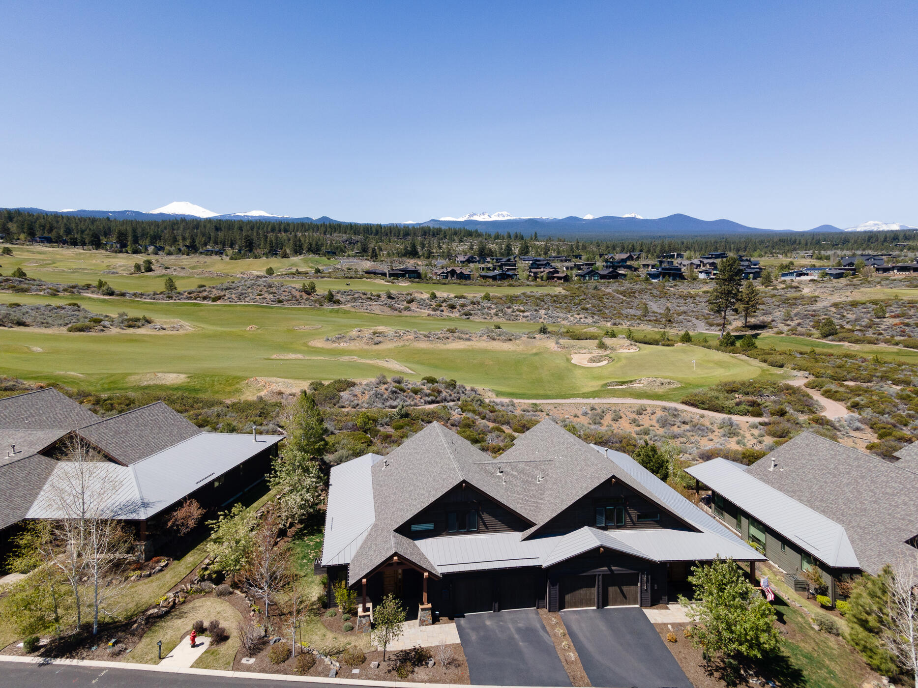 Experience lock & go living in the desirable neighborhood of Triple Knot at Tetherow Resort. Perched on the ridge of the 10th fairway, this light & airy townhome captures picturesque views of the Cascades & Tetherow golf course. The well-thought-out floorplan features a main level primary bedroom & office, w/two additional en-suite bedrooms upstairs. The open great room is perfect for entertaining, featuring a chef's kitchen w/double islands, high end cabinetry, & quartz counters w/an additional prep sink, built-in speakers in the kitchen, great room, & patio, hardwood floors throughout most of the main level, & a gas fireplace w/metal accents & elegant built-ins.  The primary suite features a spa-like bathroom w/a double vanity, walk in closet, soaking tub & a tile shower w/dual heads. With true turnkey living, you'll have time to enjoy the peaceful & private setting from the expansive, partially covered patio, the resort facilities, & the close proximity to Bend's westside amenities