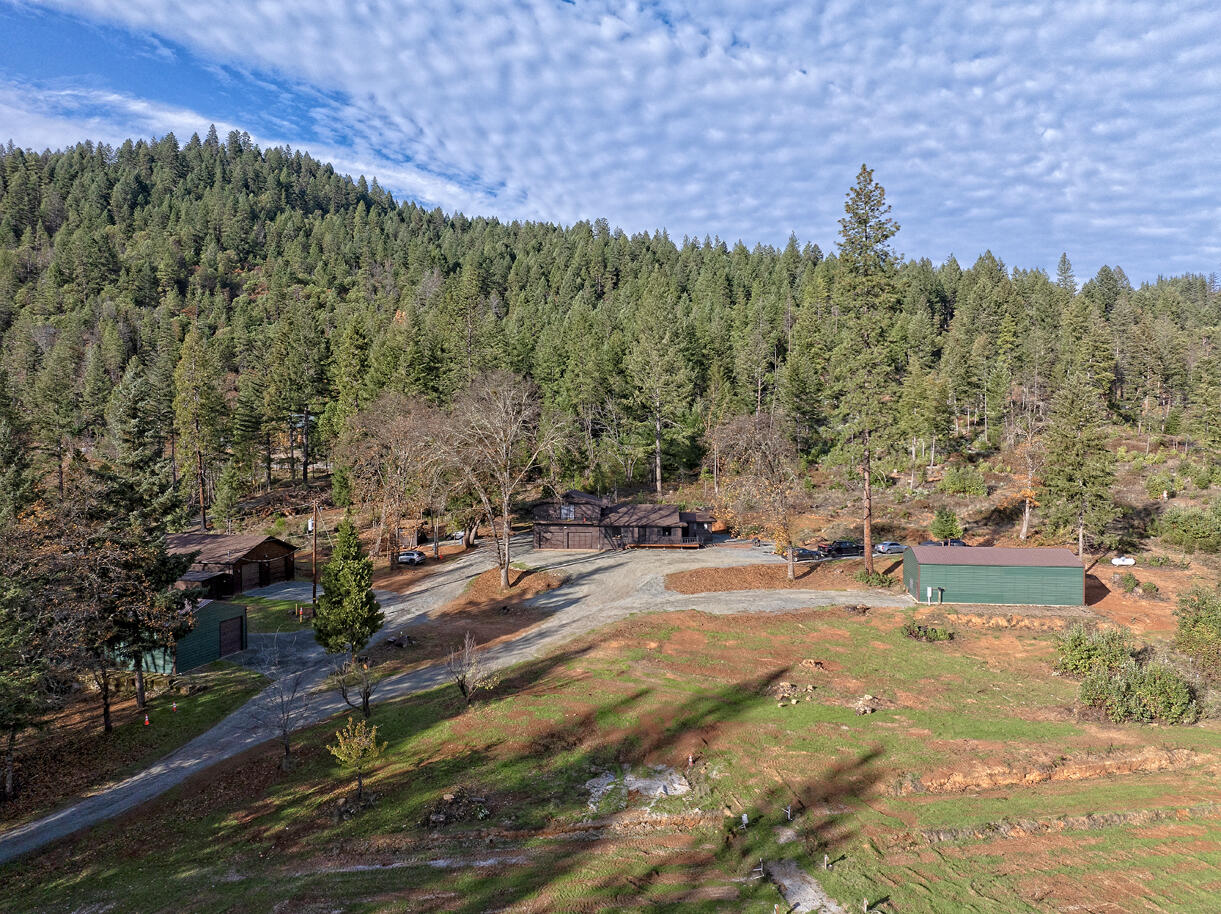 Discover 15 usable, improved acres across from the Hogs Creek Boat Landing on the Rogue River in Southern Oregon—a private, multi-use property with major upgrades. Ideal for multi-family living, agriculture, hobby farming, or a turnkey rural retreat. A gated entrance leads to irrigated terraced garden/livestock areas, fruit trees, a pond, creek frontage, recent fire clearance, and a new power pole. Three fully permitted shops (30x40, 30x70, 40x50) offer insulation, concrete floors, plumbing, electrical, climate control, plus sheds, hookups, and security lighting. The updated 4-bed, 3-bath home features new flooring, windows, lighting, paint, decks, butcher-block counters, new appliances, and improved fixtures. Systems include new smart HVAC, mini-split, climate-controlled garage, three water tanks, strong well, and a spring. A 360° roof fire-suppression system adds protection. RV hookups are in place, and the land blends utility with natural beauty—rare, ready, and versatile.