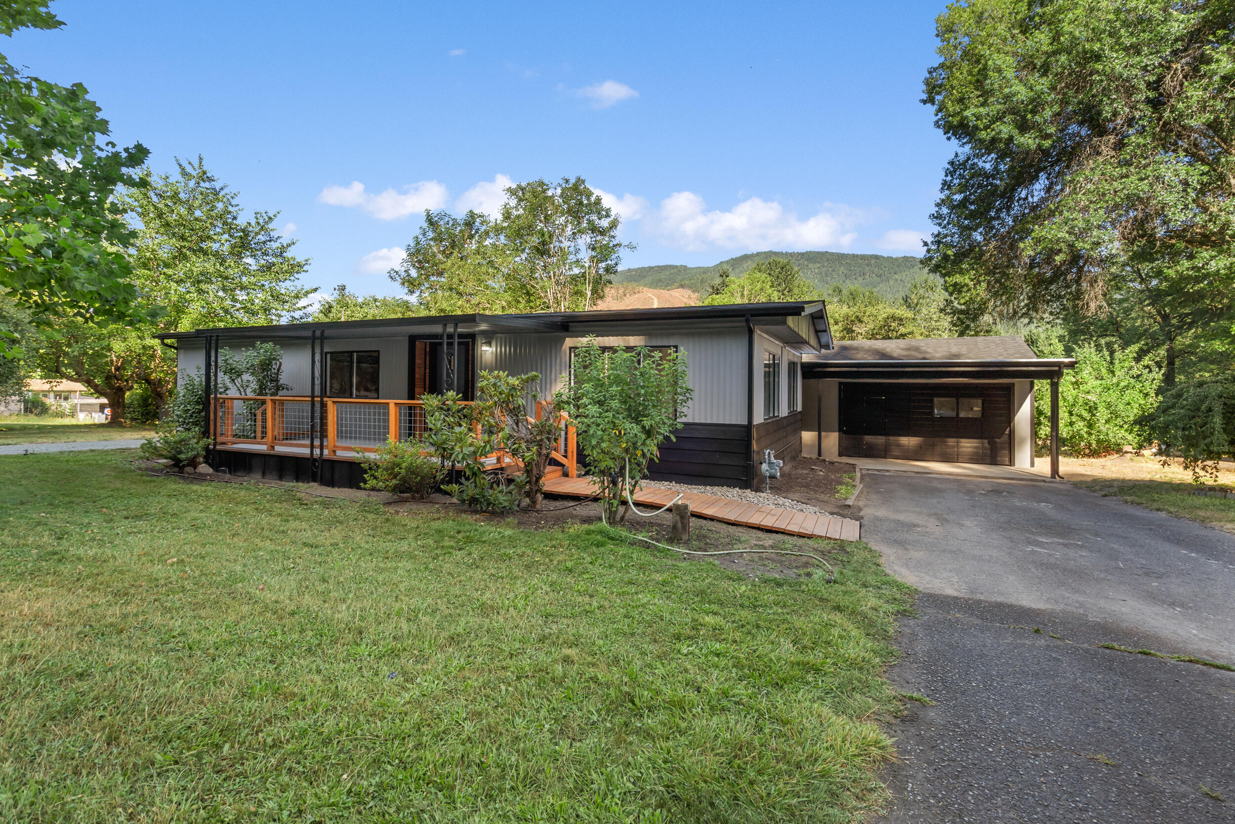 Beautifully remodeled in 2025, this spacious double-wide manufactured home sits on a spectacular 0.65 acre lot with serene creek frontage and steps leading down to the water. The property also features an oversized two-car garage with an attached studio apartment, complete with its own kitchenette and bathroom—perfect as a guest suite, rental, or private retreat. Recent upgrades include new roofs on both the main home and garage, fresh interior and exterior paint, new carpet, and luxury vinyl plank flooring throughout the main residence and studio. Enjoy the peace and privacy of your expansive lot, all just minutes from the heart of charming downtown Rogue River. Whether you're looking for a tranquil primary residence, multi-generational living, or an income-generating opportunity, this turnkey property offers it all. Don't miss your chance to own this little gem, it won't last long!