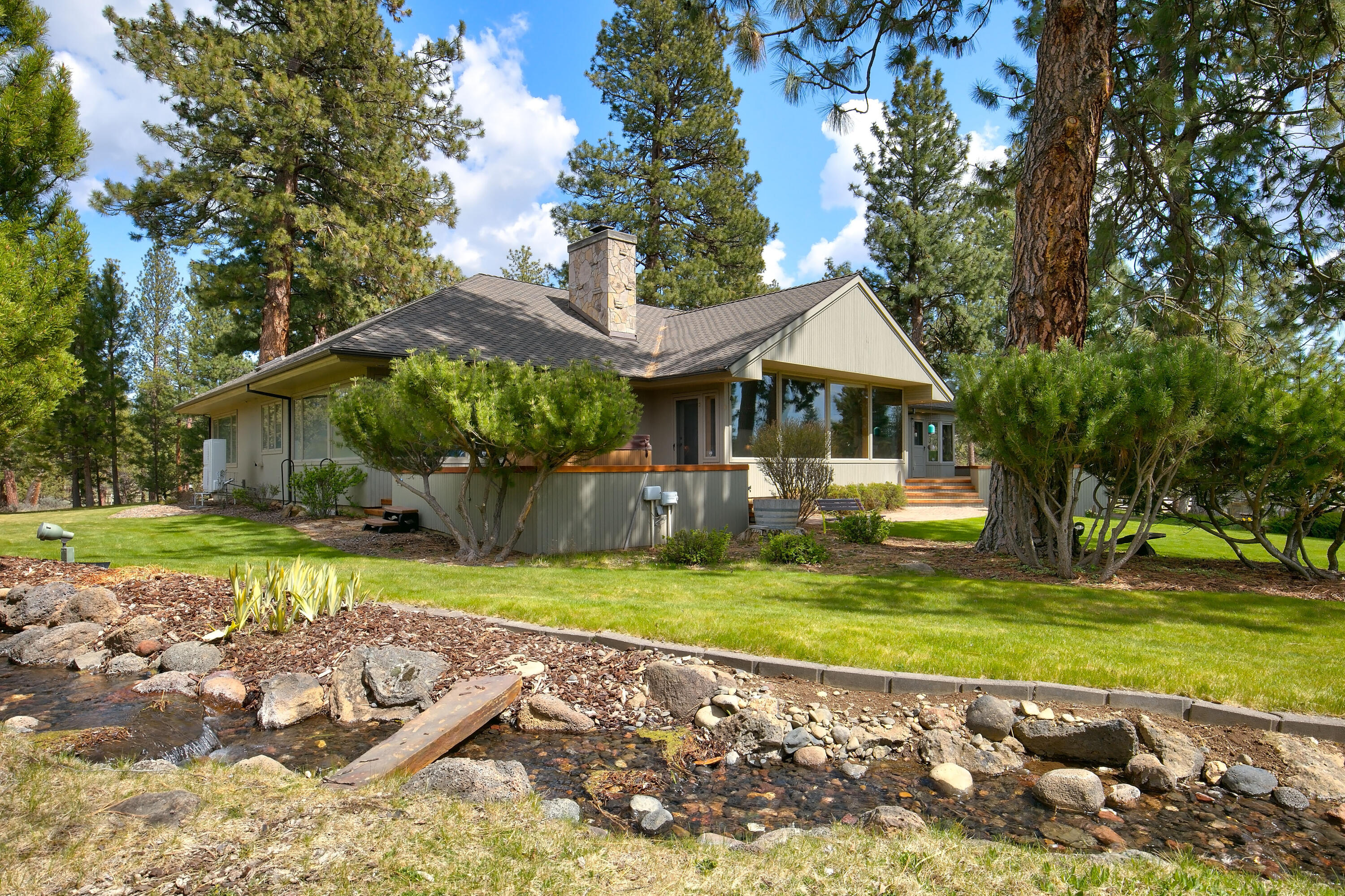 Discover your private retreat just minutes from downtown Sisters, boasting stunning views of the Three Sisters and Black Butte. This picturesque property, set on beautifully landscaped acreage, features a tranquil water feature with a waterfall and stream, perfect for serene living. The single-level home showcases a bright, open-concept layout. The spacious, updated kitchen effortlessly connects to the dining area and great room, highlighted by vaulted ceilings and a cozy wood-burning fireplace ideal for gatherings. This residence includes three bedrooms and three baths, featuring a luxurious primary suite with an ensuite bath, walk-in closet, and direct access to a deck overlooking the scenic grounds. Additional spaces include an office, laundry room, pantry, and a charming breakfast nook, thoughtfully designed for comfort. For hobbyists and outdoor enthusiasts, the home offers an oversized two-car garage and a 1,728 sq ft barn/shop, presenting endless possibilities.