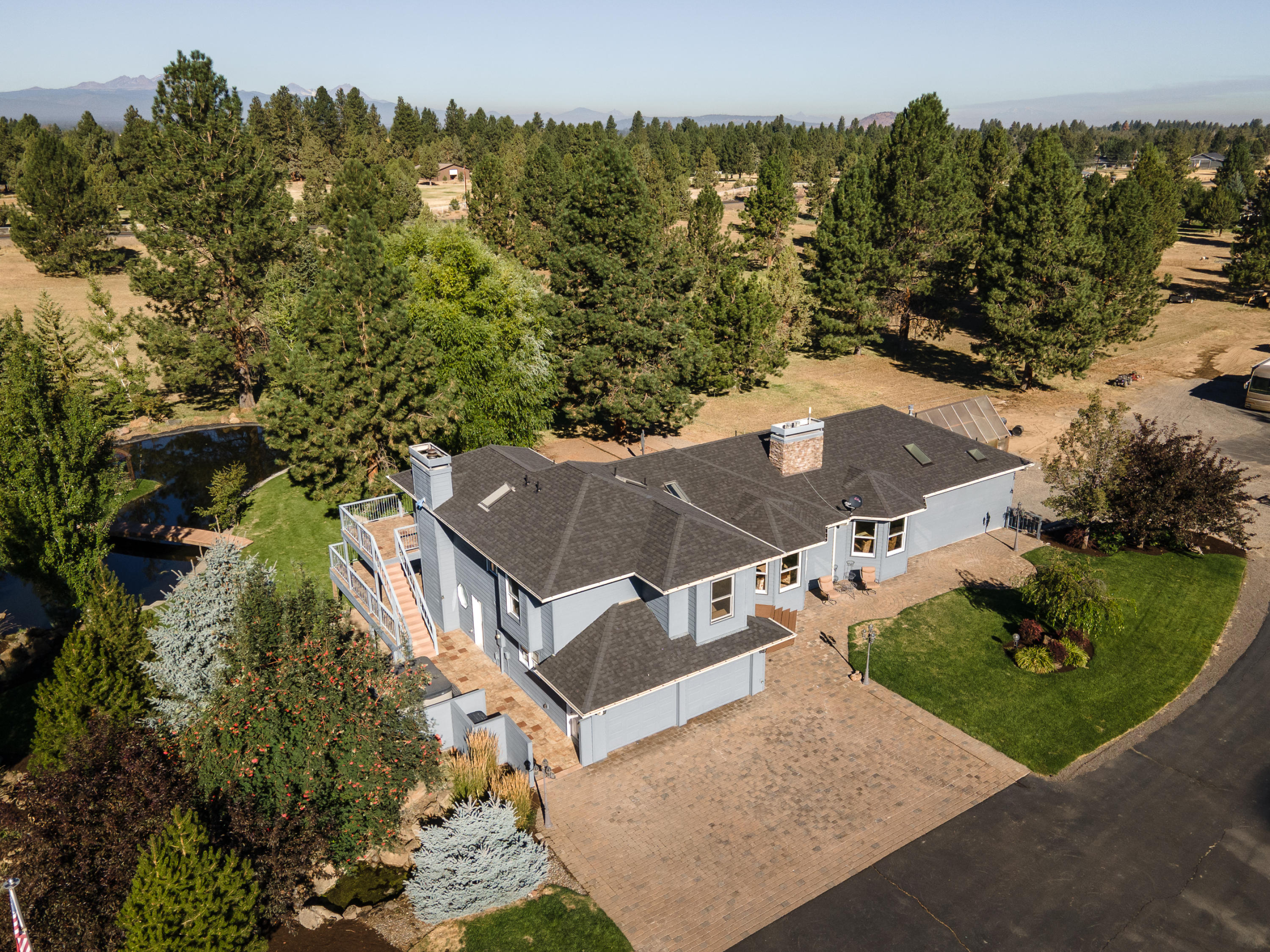 Private, park-like 9.5+ acre paradise with room for everyone and everything you love. House spans over 5200 sf with flexible floor plan ideal for living large. Host your next party or reunion in the light-filled gourmet kitchen & great room with soaring vaulted ceilings. Main level spills out onto an enormous balcony where you can watch family and friends play on the volleyball court, stroll the lushly-landscaped grounds with oversized pond and toast marshmallows around a charming stone fire pit. If you need peace and quiet, tuck into your own 1200 sf master suite with fireplace, walk-in closets and spa-like bathroom with giant tiled shower and jetted tub. Roomy upstairs has a second master suite, two bedrooms and full bath. Downstairs is an oasis unto itself with it's own kitchen, living room, bedroom, bath, sauna and separate entrance. Steps away is a 48 x 60 shop w/14 ft RV door. This fully-insulated bonus space is perfect for home biz, gym, game room – whatever you dare to dream!