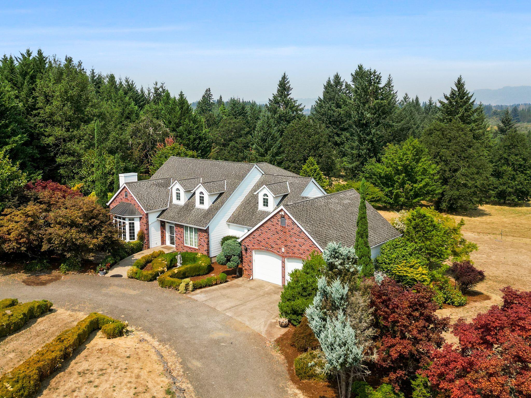 Dream home, property & location! 4-bed, 2.5-bath stunning home on 17+ acres w/irrigation. 3,350 sq.ft., with 2006 sq.ft full daylight basement.  Grand vaulted ceilings, hardwood floors, gas fireplace, and French doors to balcony overlooking beautiful pond & grounds. Spacious kitchen w/island, double ovens, trash compactor, pantry and breakfast nook. Stately library with fireplace and extensive wood finishes with built-in bookshelves.   Formal dining area includes a butler's pantry. Primary suite w/balcony, spa-like ensuite bathroom and two walk-in closets. . Daylight basement, rec room, patio access & storage rooms. Expansive 48'x60' shop, garden shed, 3000 gallon cistern, 10 acres of marketable timber, fruit producing orchard, kitchen garden & mature landscaping.  Large pond for irrigation and for your enjoyment.  Circular, graveled driveway, stone pillar monuments at entrance. Located at end of dead-end street.