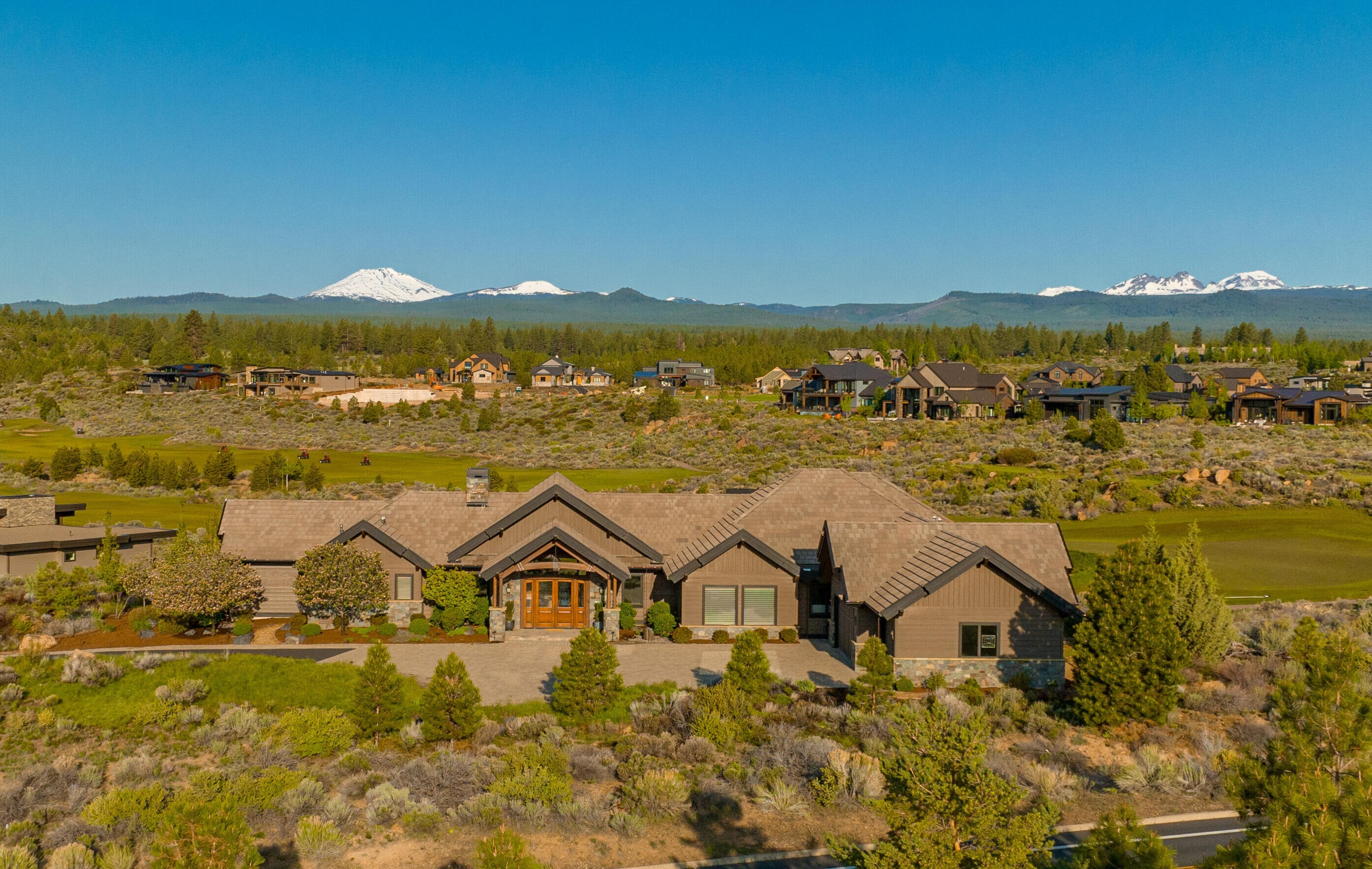 Elegant, yet undeniably welcoming. Dramatic but still imminently tranquil & private. All of this, and more, intertwine to give this luxurious custom built house the inherent comfort of home. 19.5' ceilings and floor to ceiling windows in the great room draw the eye across greens & fairways of Tetherow golf course to magnificent Cascade Mtn. views as your backdrop. Unlock your culinary genius in a chef's kitchen with an induction cooktop, large island with prep sink & walk-in pantry with a 3rd sink & loads of storage. Three ensuite bedrooms including a primary suite with a 15' vaulted ceiling as a gateway to mountain views, a generous bathroom with soaking tub & walk-in tile shower and heated floors. Beautifully appointed flex room features Cascade Mtn. views, private bathroom, built-ins, fireplace & vaulted ceilings. Enjoy those spectacular views from a private covered patio with stone fireplace & in ground spa with fire bar, buffered by natural scape common space on this .89 acre lot.