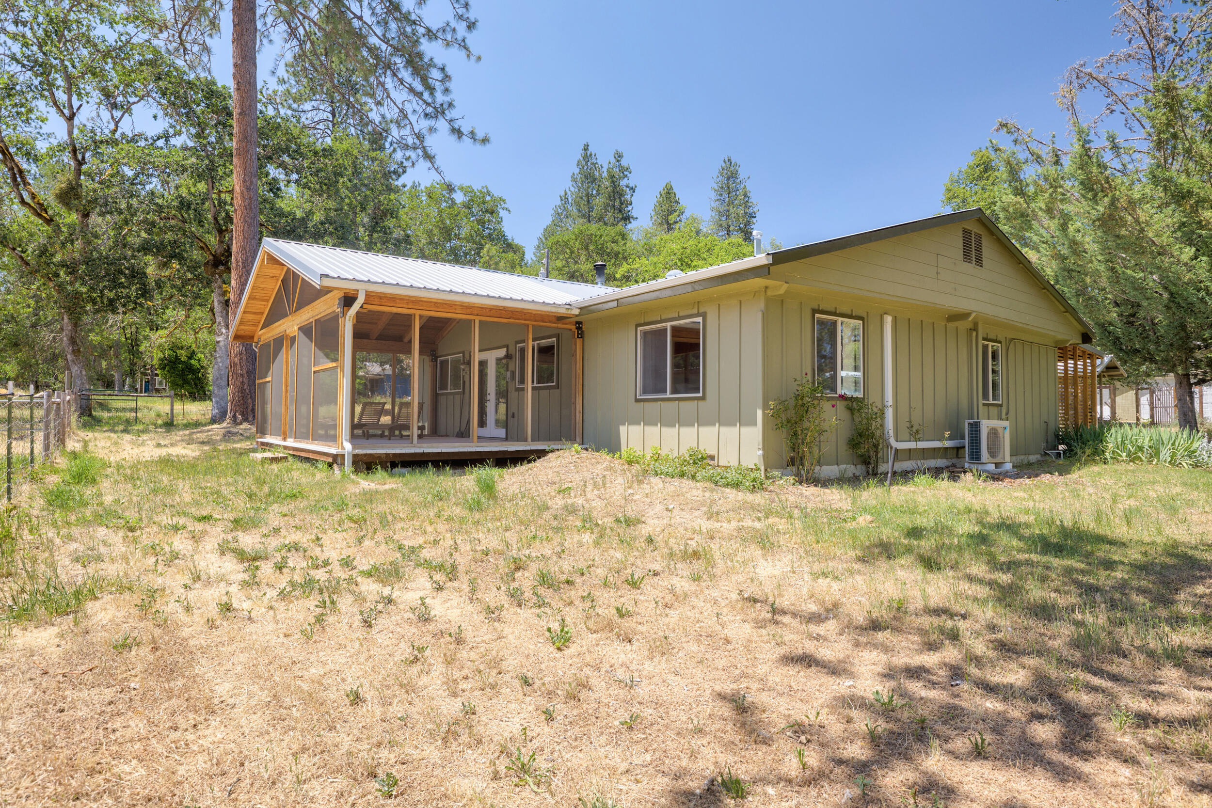Peaceful mini homestead in Williams with HUGE shop! This well-maintained 1,280 sq ft home sits on 2+ acres and features exposed beam ceilings, heated bathroom floor, upgraded vinyl windows, mini splits, updated appliances and a cozy wood stove. Enjoy two screened-in covered porches perfect for relaxing. The incredible 2,348 sq ft garage/shop includes it's own 200-amp service, four garage doors - two pull through bays in the center and one on each end - plus RV hookups in back. The property is fully fenced with the perfect mix of sunshine and trees with a chicken coop, multiple animal shelters and fenced areas for animals and gardens. Excellent water and irrigation throughout make this an ideal setup for self-sufficient living!