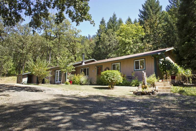 Park like 5 acres in ideal location in the Illinois Valley with a spring fed pond, lovely garden areas, beautifully wooded acreage off Dick George Rd on dead end lane. Home was updated between 2008 and 2012 with no. 2 maple wood flooring, awesome custom cabinets, ceramic tile floor n game room and large concrete front porch area. Also has 3.5 acres fenced for alpaca, llama, or ?. Beautiful property, completely surveyed, attached shop/garage. Insulated pump house and covered wood storage. Landscaped lawns and ornamental plants, firs, and madrone trees. Lovely place to call home!