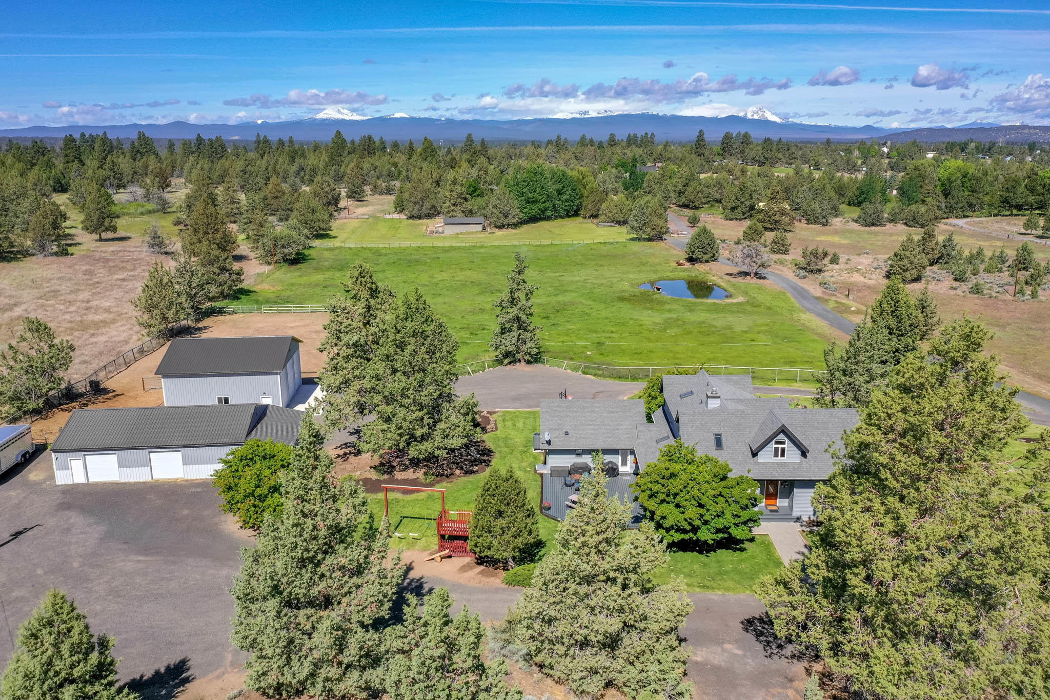 Mountain views from this gorgeous 5 acre property boasting a 2 stall barn w/ tack room and workshop, and 1300 sq ft shop on a separate meter with 14x11 roll up doors. Bring your animals, RVs, toys and equipment as this property will house it all! Newer SS appliances, large island, oak hardwood floors and sun-room round out the kitchen and dining area. This lovingly cared for 4 bedrooms plus office home has a spacious living area and bedrooms with lots of windows showcasing the property and views. Plenty of decking surround this house, making it perfect for entertaining and enjoying the sunset and flowering trees. This property is close to town but far enough away to feel like your own private sanctuary. New heat pump and humidification system added in 2017.