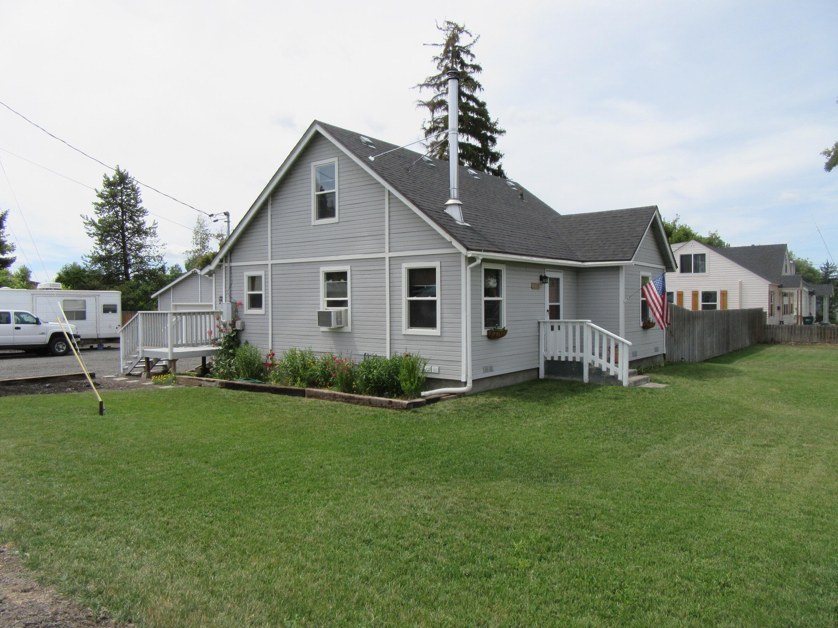 Centrally located, well maintained home on large lot with RV parking. Ready to move in with new central heat furnace (A/C ready), 2-year-old water heater, natural gas, KID water for lawns/gardens.  Double-paned windows with shades. French door off dining area to outside deck. Spa tub in bathroom and two bedrooms downstairs/additional large bedroom upstairs. Window air conditioning upstairs and down, wood stove, engineered hardwood floors downstairs, wood floor upstairs. Basement room for storage or canned goods. Kitchen has soft-close hardwood cabinets, garbage disposal, ice maker in refrigerator, dishwasher and laminate countertops. Large two car garage with partitioned 8-foot-wide storage area. Yard shed with cabinets and countertop for tools/mower and gardening needs. Fenced chicken coop with henhouse, fruit trees, berries, and raised beds in the garden. Outside covered wood storage in backyard and area for BBQ's and gatherings. Fenced yard.