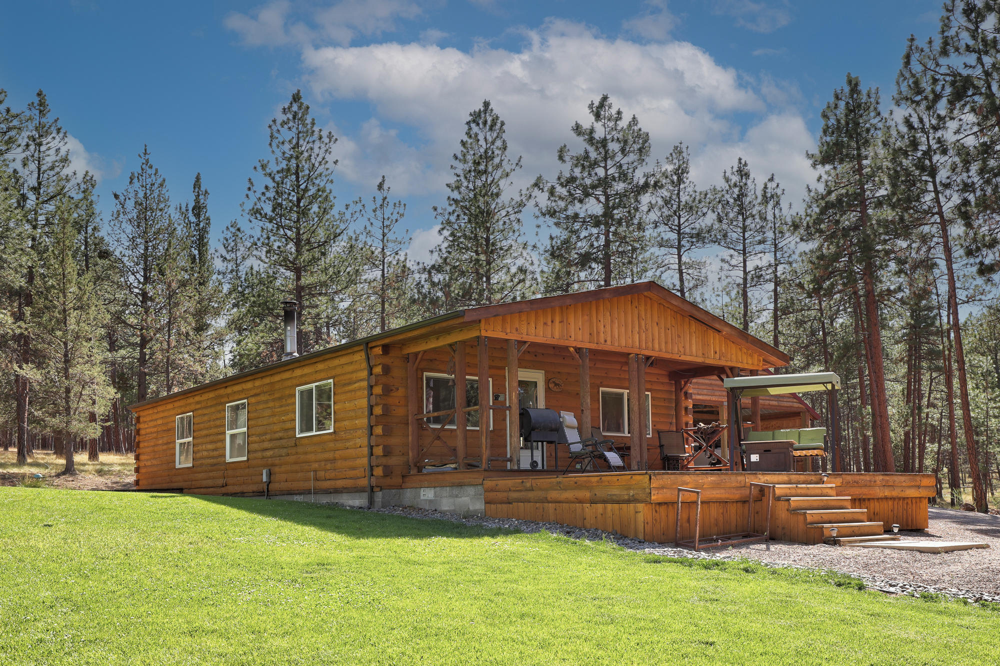 Sitting on over 9 private acres adjacent to Deschutes National Forest land, this well-maintained property offers a quiet setting just minutes from Sisters.The home with log cabin siding stays comfortable with central heating & cooling, and wood-burning fireplace. The kitchen features Stainless Steel appliances. Outside, the front deck and back patio with hot tub offer plenty of space for outdoor living. The 1920 sq ft barn has stalls and two 24x12 hobby rooms. Additional outdoor features include: multiple covered parking areas, garden with drip system, greenhouse, dog kennel, and poultry coop. The property is fenced and cross-fenced. The back half of the property offers a build site with easterly views. The roof is less than 5 years old and the exterior of the home, including decking, was re-stained in 2021. Enjoy the peaceful setting of the forest while being close to town.
