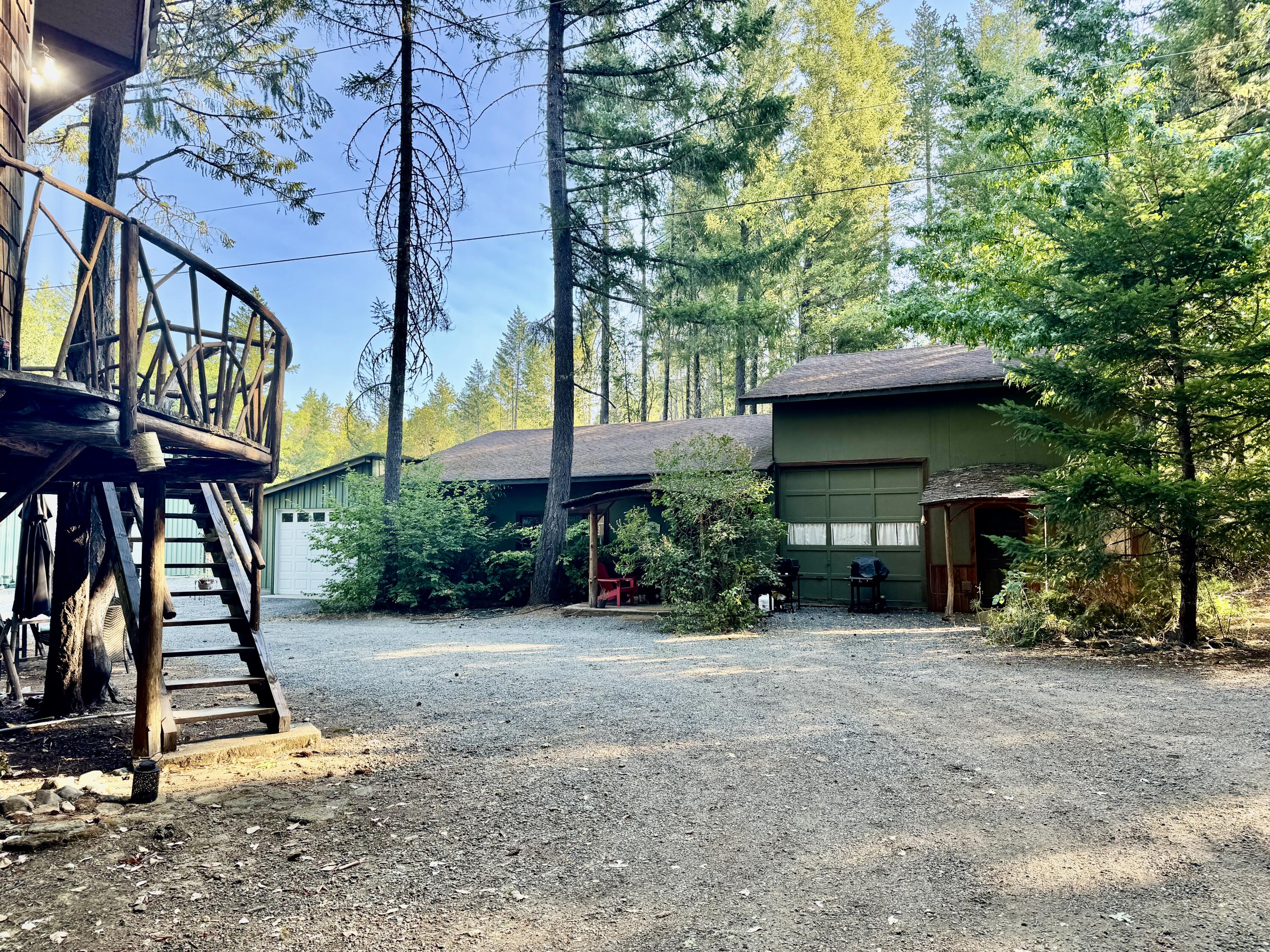This home is a MUST See!  Sitting on beautiful 15 acres adjacent to the Illinois River with private river access and backing up to BLM Land for privacy.  This unique 2,600 sq ft home features a wide open floor plan, high ceilings, primary down stairs, cord wood art log wall, cement floors, and a roll up door allowing for easy access the outdoors nature or for a vehicle access to the main living room.  The property features a one of a kind 200 sq ft guest treehouse with private bath and toilet.  A huge bonus is the  40 X 60 shop with 5 rooms, loft and 400 amp panel inside....a man's dream!  The property also comes with 2 green houses, a irrigated gardening area and 3 shipping containers - 2 are connected by a mini shop in between.  Lots of privacy with a gated entrance.  There is a 3500 sq ft log Cabin next to this house (great for multifamily living)  that can be purchased together with this home for additional price.....can be negotiated....Bring all offers!