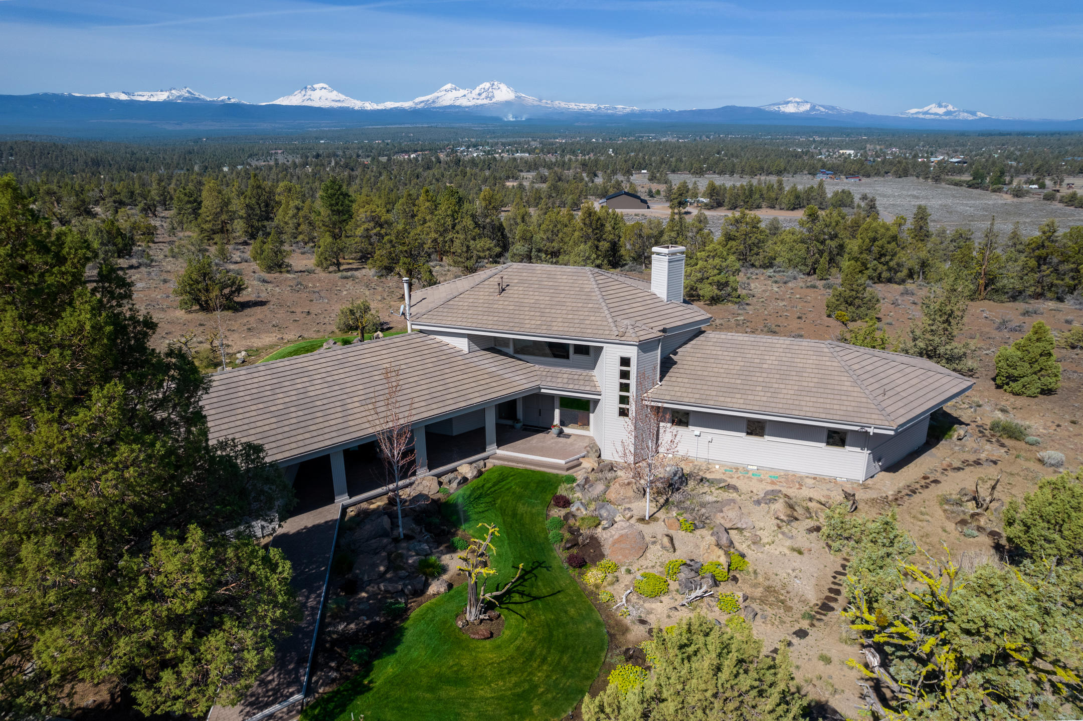 Perched on 25 private acres in Tumalo, this contemporary Northwest-style home offers panoramic Cascade Mountain views. A commitment to quality is evident from the gated entry, to the concrete tile roof and professional landscape design. Inside, abundant windows allow for ample natural light and mountain views from every room. The living area has 10' box beam ceilings, clear alder trim, and wood-burning fireplace with custom steel doors & clear alder mantle. Well designed kitchen with granite countertops, stainless steel appliances, and island with breakfast bar. Upstairs, the luxurious primary suite features walk-in tile shower, soaking tub, walk-in closet, and balcony to soak up the views. There is a second primary suite on the main floor. Outside, the concrete paver patio provides plenty of space for outdoor living, cedar spa, and brick wood-fired grill. Enjoy the tranquility of Tumalo while being only minutes from Bend, Sisters or Redmond. Located in Sisters school district.