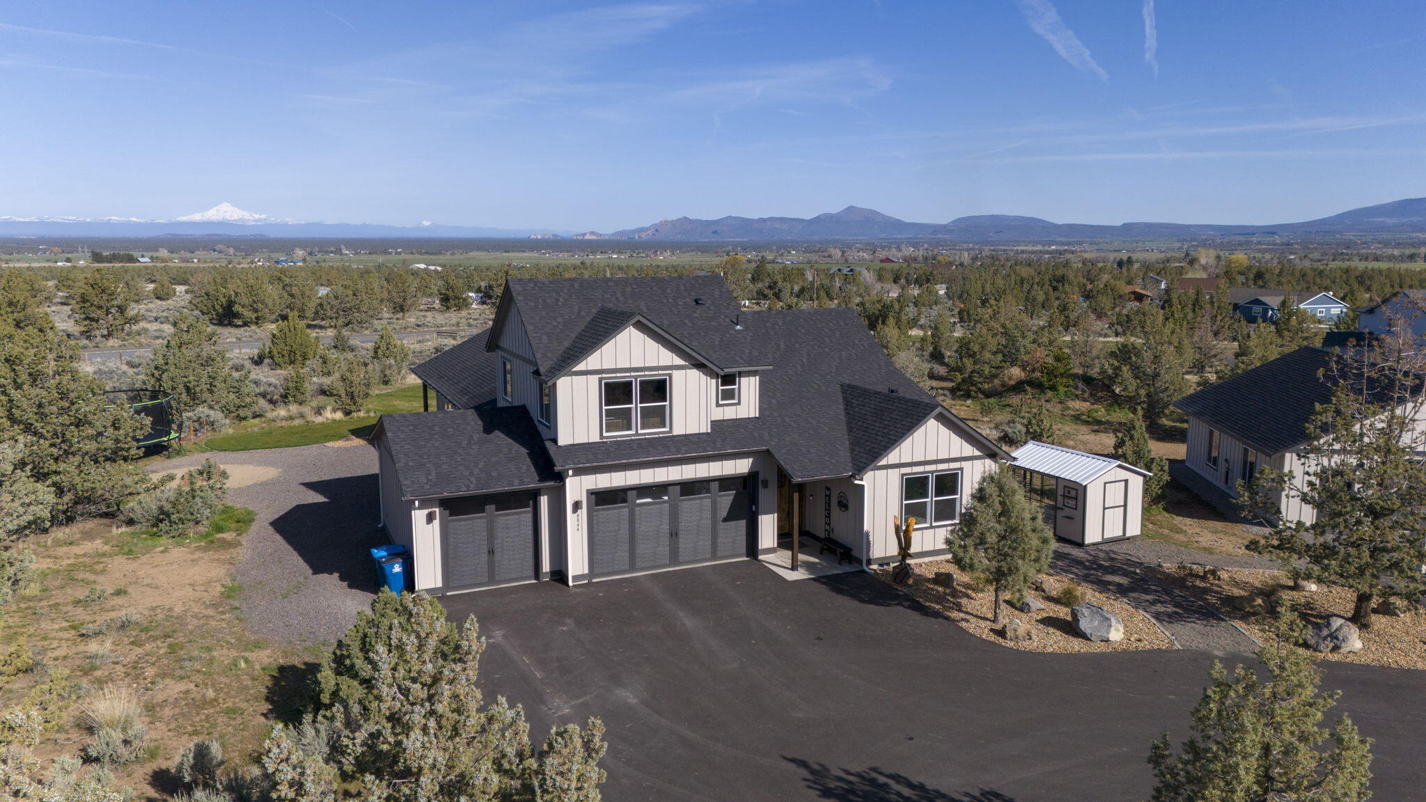 Beautiful 2022 home with 3-car garage in Powell Butte on 4.84 acres on a paved dead-end road. Featuring open concept living/dining/kitchen with vaulted ceilings, LVP floors, oversized windows, and amazing views. Main room separation, utility room w/sink and office. Jr. suite/bonus room above garage! Large kitchen features wood cabinets, island/eating bar, walk-in pantry, SS appliances with quartz countertops throughout. Covered front porch and a 15'x40' covered back patio w/ exposed wood beams makes for the perfect spot to watch the sunset & enjoy your backyard views! Main room features a large walk in closet, tile shower, enclosed toilet, double sinks, and door to patio. Fully fenced perimeter, automatic entry gate, asphalt drive, landscaped, hot tub, 30x50 shop with two additional 12X50 covered/sided lean-to, 200 amp electrical service to shop with 2-14x12 automatic garage doors. The detached 30x32 rec room/garage features vaulted ceilings, heated with a pellet stove and insulated!