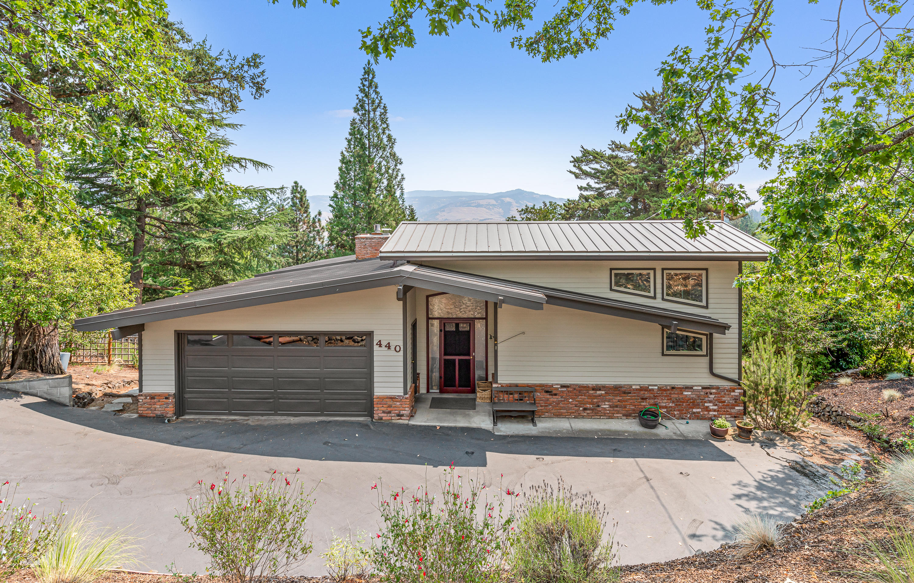 Elegant and spacious mid-century home with dramatic views, located in a highly desirable neighborhood nearby hiking trails, Lithia Park, and downtown Ashland. Main level features vaulted ceilings, skylights, slate entry, maple hardwood floors, kitchen with granite counters and dining bar, butcher block island with prep sink, double ovens, 5-burner gas range, glass-fronted display cabinetry, adjacent breakfast nook, pantry and laundry room, expansive view deck, living room with exposed beams, gas fireplace with brick hearth, built-in shelving, half-bath, along with the master bedroom with high ceilings, walk-in closet, and full en-suite bath with slate flooring, dual vanity, travertine tilework, shower, and jetted tub. Lower level has three additional bedrooms, two full bathrooms with slate floors and travertine-tiled counters, family room with gas fireplace and wet bar, wine cellar, utility room, and patio with sauna and hot tub. Inquire with agents for complete list of improvements!