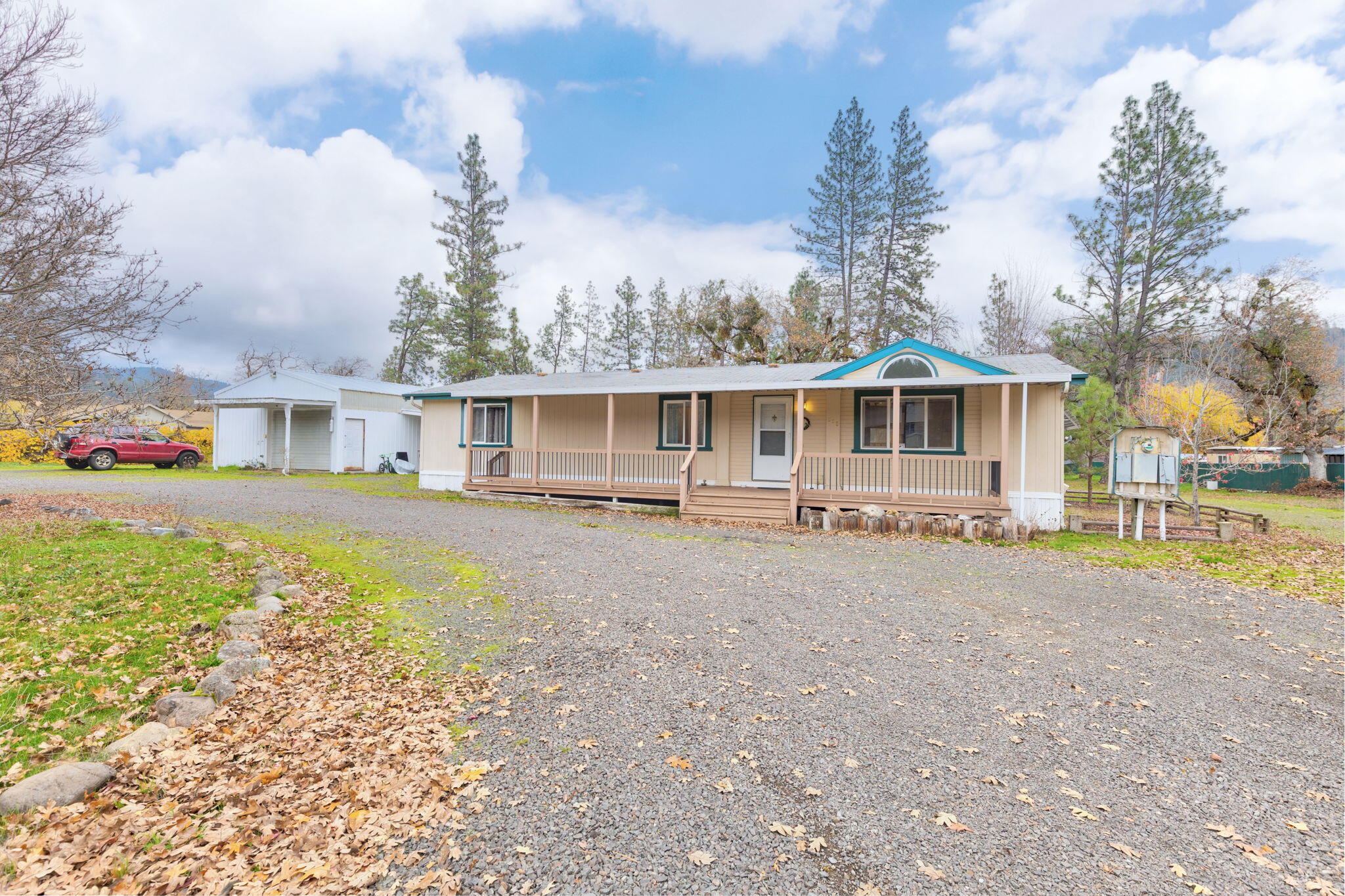 Discover rural living on 2.13 level, beautifully usable acres with a 3-bedroom, 2 bath double-wide home. A circle driveway welcomes you onto the fully fenced property dotted with old oaks, grapevines, and plenty of open space to garden, relax, or expand. Enjoy covered front and back porches perfect for year-round outdoor living. The property offers excellent functionality with multiple sheds, a full RV hookup, and a 20' x 30' shop with 2 attached carports - ideal for vehicles, projects, or extra storage. Inside, the home features a comfortable layout with spacious living areas and a new dishwasher in the kitchen. Located close to both the Rogue River and Lost Creek Lake, this is an ideal base for fishing, boating, and outdoor adventures. A wonderful blend of practicality and natural beauty - ready for your country lifestyle.