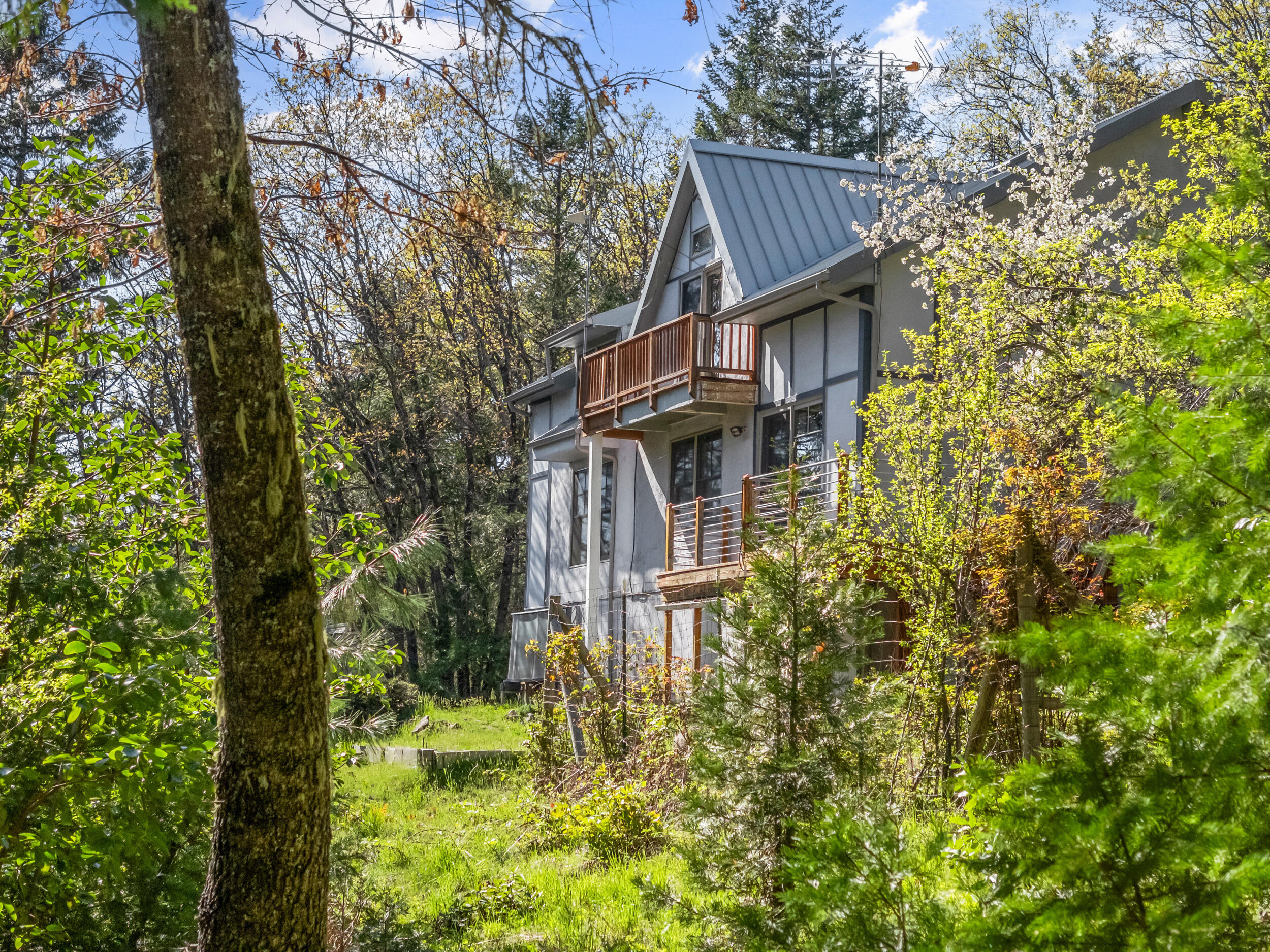 Versatile, spacious, and thoroughly updated home on private wooded acreage in the Cascade-Siskiyou National Monument - just 14 miles from Ashland! Main level features a new kitchen with granite counters and island, walk-in pantry, glass-fronted display cabinets, all new stainless appliances, informal and formal dining areas, double-height vaulted ceilings, living room with built-in entertainment system, wood cooking stove with soapstone surround, family room, and powder room. Upper level with three vaulted bedrooms including primary with private balcony, two powder rooms with access to soaking tub and tiled shower, plus a loft area with skylights. Lower-level workshop or office studio with French doors and utility storage room. Solid frame construction with strawbale insulated walls, radiant heated floors, energy-efficient double-paned windows, concrete stucco exterior, and metal roof. High-speed internet via Greensprings Broadband Coop. Inquire for details!