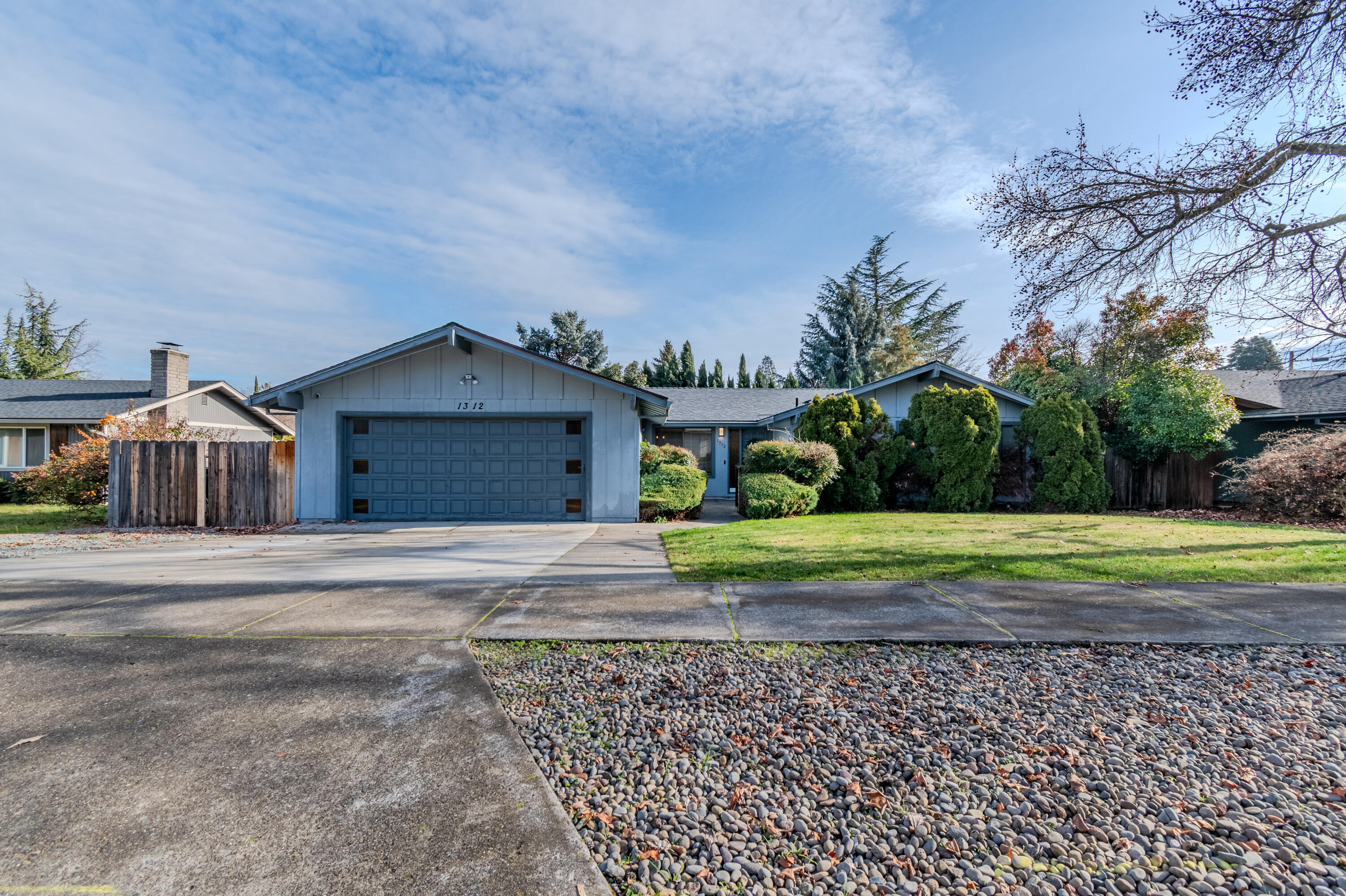 Affordable East Medford home located in the Lone Pine School District is now available!  This 3 bedroom, 2 bath home features separate living and family rooms with double sided wood burning fireplace with floor to ceiling rock surround, vaulted ceiling with open beams and ceiling fans.  Kitchen has a breakfast bar and is open to the family room that has a slider that accesses the newer composite deck and backyard.  Primary bedroom is a nice size and the ensuite bath has two separate vanities and an enclosed shower and wc.  Newer roof and floor coverings.  Situated on a fenced .18 acre lot with in ground sprinklers/drip front and back as well as a gated small RV area to the side of the garage.  A one year First American Home Warranty is included.  Seller is related to the listing agent.  ...Welcome Home!