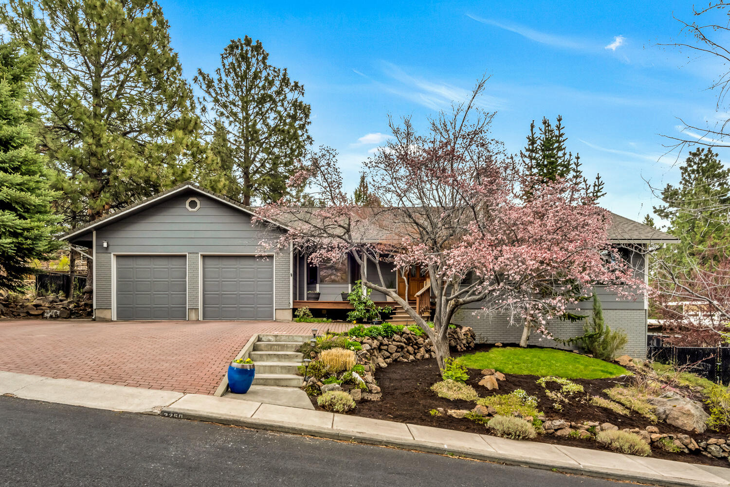 This private sanctuary is nestled on a quiet street in Bend's desirable West Hills neighborhood. Expansive windows fill the vaulted great room with abundant natural light, illuminating a living space with stack stone gas fireplace, gleaming Brazilian cherry hardwood floors & remodeled kitchen with extensive granite counters, quality appliances & a large breakfast bar. Enjoy summer meals and impressive easterly views from the brand new Trex deck overlooking a fully fenced & landscaped backyard. From the wooden bridge & terraced garden spaces to the flowing water feature, hot tub area & separate koi pond, this private backyard provides a tranquil, peaceful respite.  Main level primary bedroom includes spa like bath with glass enclosed tile shower & soaking tub. Two guest beds, updated baths,  bonus room & attached 2 car garage complete the home.  Separate 28'x16' RV garage/shop with tall door & gated, concrete drive may offer potential for an ADU.  This property is truly one-of-a-kind!