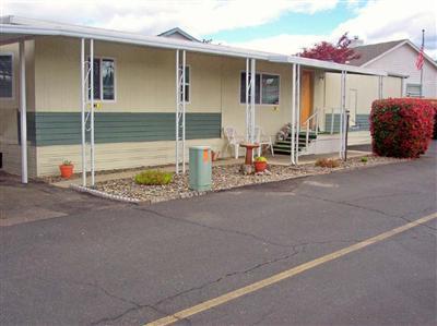 This single-wide mobilehome is terrific! It has the feel of a double-wide mobilehome with it's pop-out in the living room & a bay window at each end. There are 2 bedrooms and 2 bathrooms, a large open kitchen, a beautiful private backyard with grass & flowers, & it has an extra parking place! Located in Rogue Lea Estates (55+) there is a lake to fish in without a license & an active clubhouse. Nice neighbors in a safe and caring environment makes for comfortable living & it's close to everything! Come take a look & you'll want to stay!