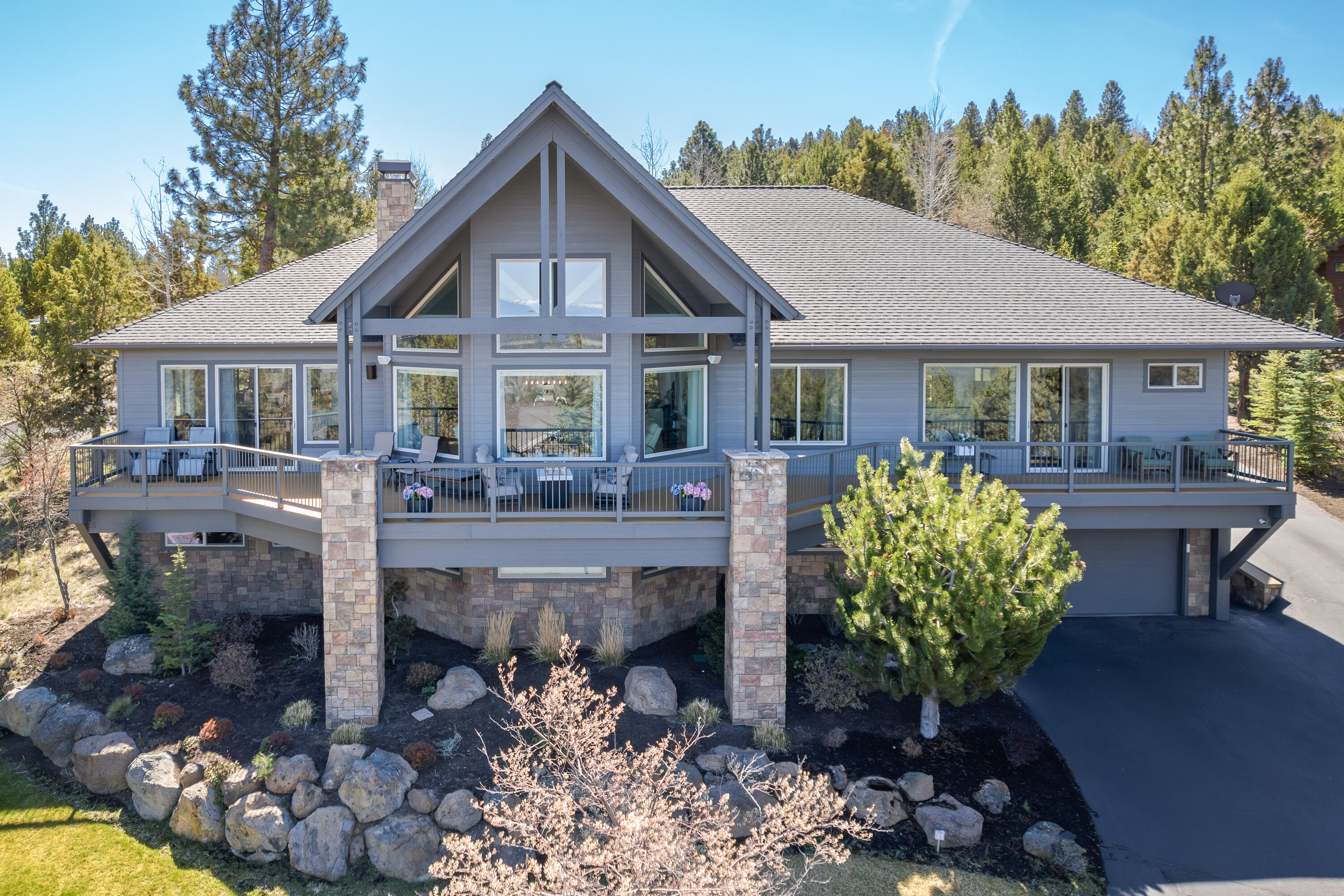 VIEWS galore! This stunning contemporary Awbrey Butte home combines modern design with thoughtful functionality, offering ample space for daily living and entertaining. Enjoy unobstructed Cascade Mountain views from the west and north that fill the home with light and scenery. The main level showcases an expansive great room with formal/informal dining, multiple living areas, a custom double-sided gas fireplace, beverage bar, kitchen, office, laundry, a luxurious primary suite, and junior suite. Upstairs features a large bonus room/sleeping area. The lower level includes a game room, theater, 2 guest bedrooms, bath, and abundant storage. The heated lower garage fits 4+ cars; the upper garage offers 2 more spaces at the main entry. The level, private backyard includes a covered patio, built-in fireplace, and swing. Call today for your private showing!