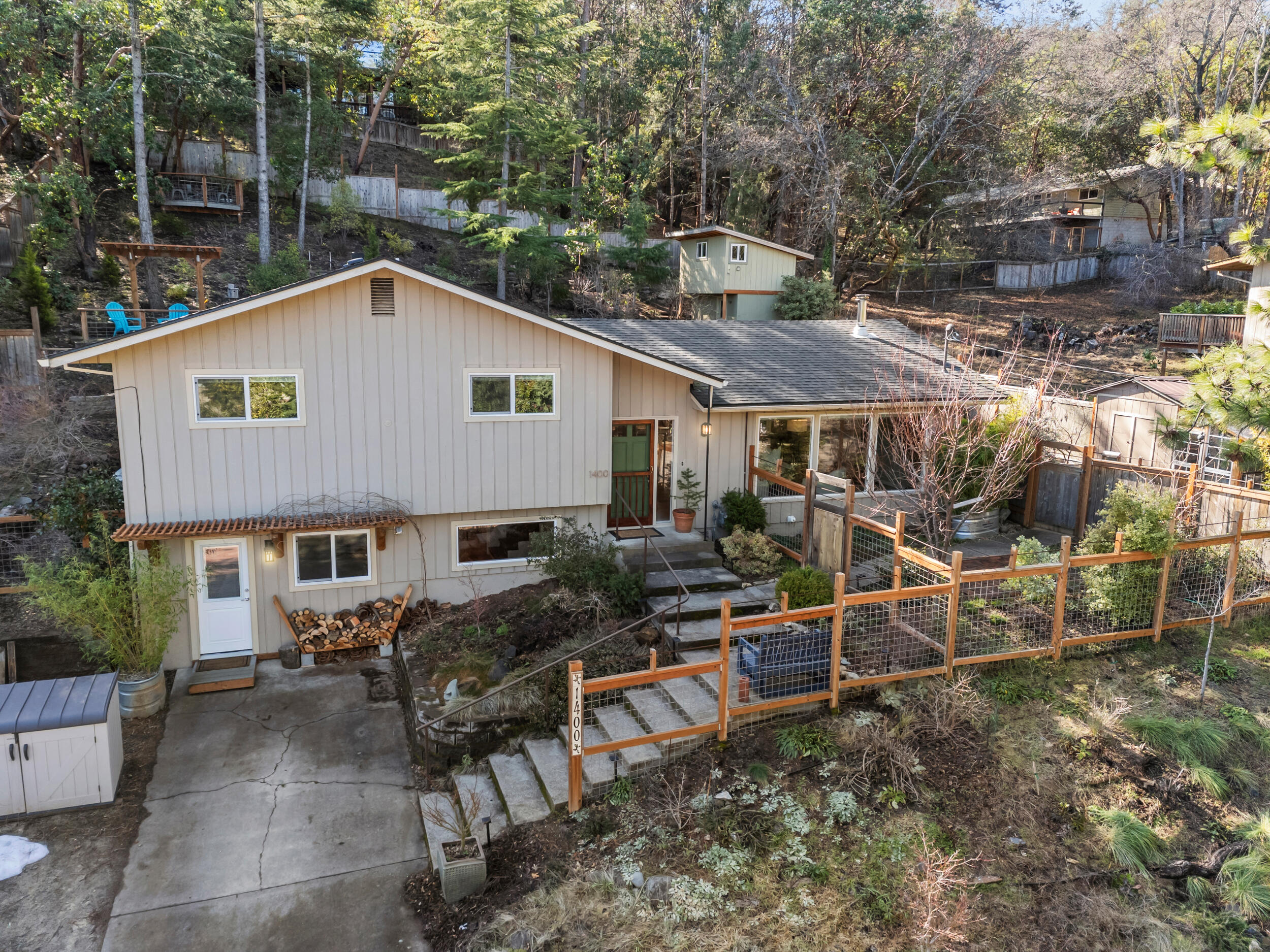 Nestled above the boulevard in Ashland, this mid-century modern home offers a unique blend of classic design and modern updates. Oversized windows frame beautiful mountain views, and fill the space with natural light. A new Morso wood stove adds both warmth and ambiance to the living space; and you'll stay comfortable year-round with the new high-efficiency heat pump (with air filtration system) and gas furnace. The kitchen features a Blue Star gas range, quartz counters and new lighting, while the updated main bathroom provides a spa-like retreat, with a walk-in tiled shower and new vanity. The lower level offers incredible versatility with a multi-use space complete with its own entrance, bathroom, and kitchenette - perfect for long term guests or a home office. Outside, a fully fenced yard with mature landscaping provides a serene escape, complete with winding pathways, multiple seating areas, a gazebo for outdoor dining, cedar sauna, and outdoor shower!