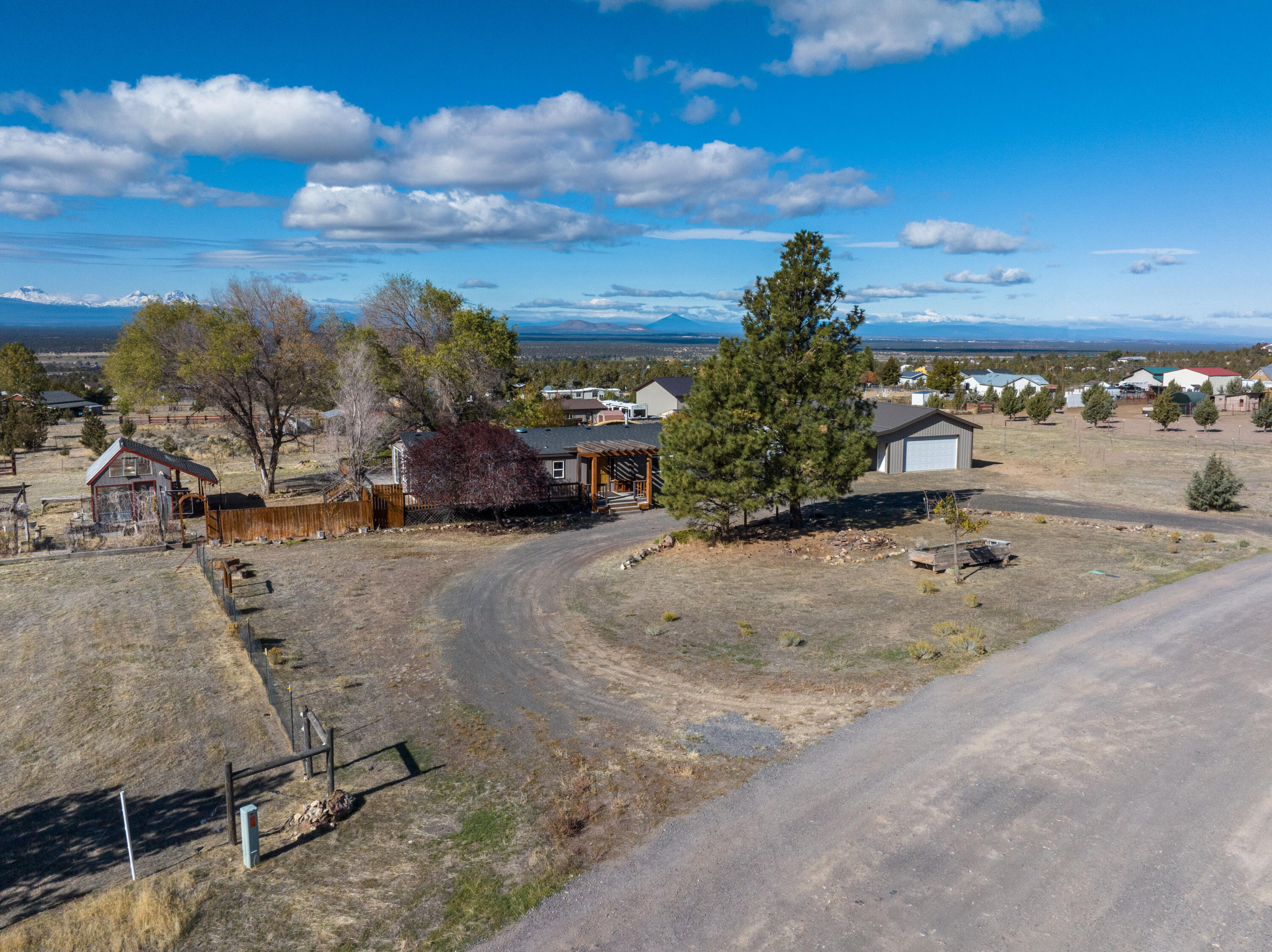Stunning Cascade Mountain views from this 2.1 acre Powell Butte home on acreage! This 1,848 sq ft home features 2 bedrooms, 2 bathrooms, a cozy living room, and a kitchen with custom cabinets and granite countertops. The family room, warmed by a wood stove, opens to expansive decks perfect for soaking in the scenery. The property boasts a greenhouse, fenced garden, a 1,152 sq ft garage/shop with attached carport/equipment storage, and a separate storage building. Your dream of serene country living awaits!