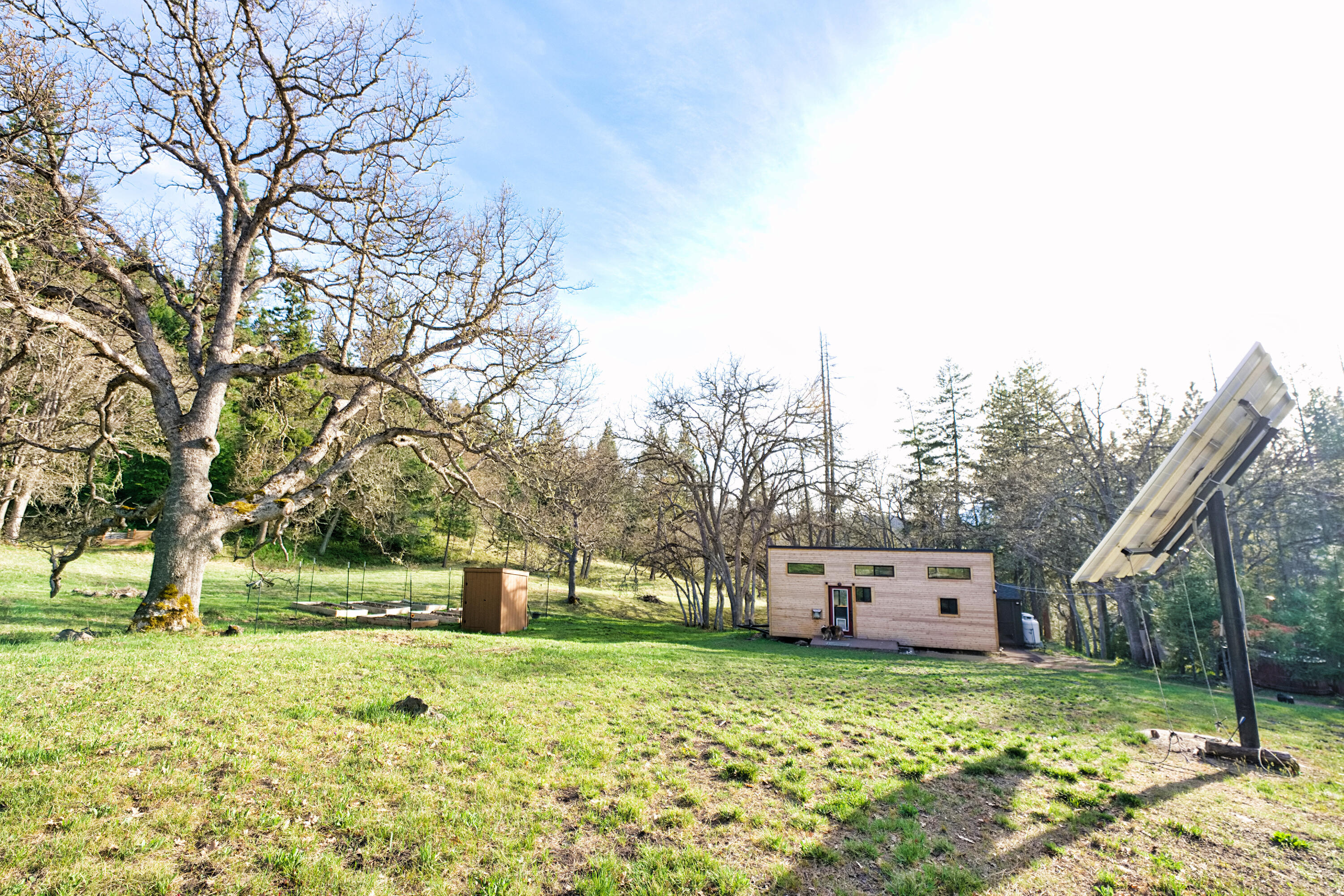 Come cool off at this mountain oasis! This gorgeous 5.44 acre parcel has 9 structures on it with a professionally built tiny home, 3 detached bedrooms, a central communal kitchen/bathroom, and several utility buildings. This property is served by a 1.6 KWH solar system array, however, power is available at the driveway if desired.  A sand filter septic system was installed in 2015 and the well produces a consistent 7gpm - also served buy a 1500 gallon gravity fed holding tank. This property would be a perfect group recreational property, a vacation rental (sleeps 10), or great for building your dream home! Many possibilities exist. Buyers to perform all due diligence related to property, uses, and structures. Sale includes washer/dryer, backup generator, wood-fired hot tub, solar equipment, and sheds. Contact Listing Agent for possible financing options. Owner may be willing to finance with large down. Buyer to perform their due diligence for desired use of the property.