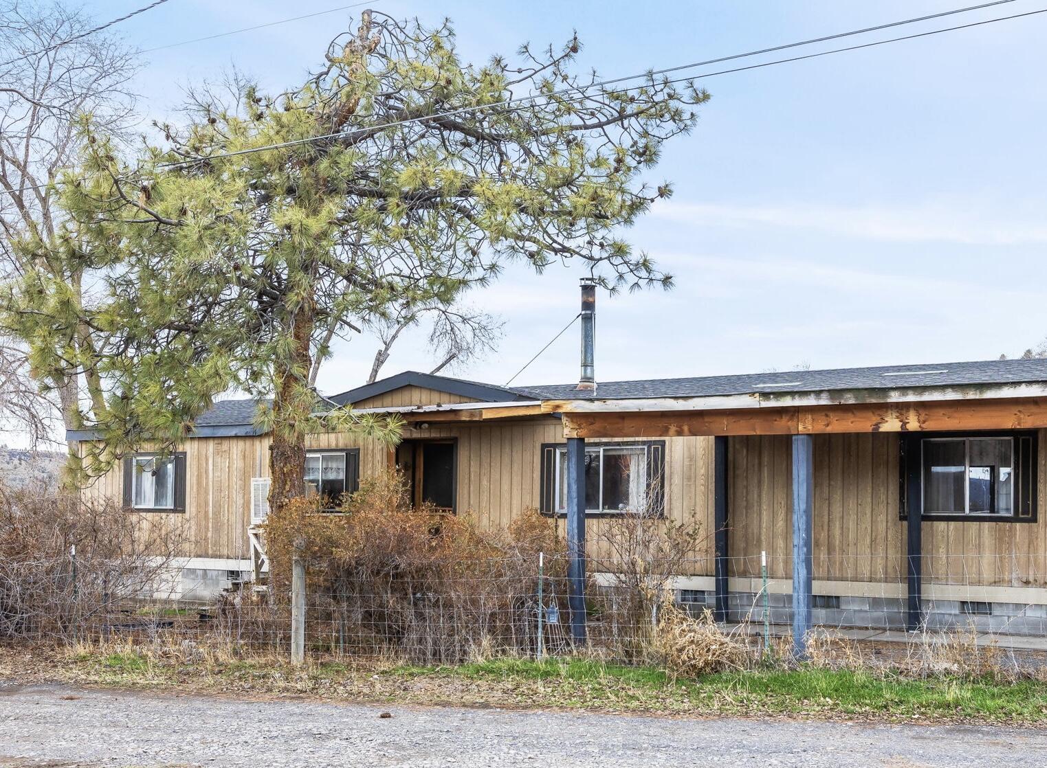 Here is your chance to own a mini farm, just on the outskirts of town, in a highly desirable area adjacent to hay fields & farm land. This 1,768 sq ft Oak Springs
Manufactured home is extremely spacious w/lg great room w/vaulted ceilings, split floor plan with 2 large bedrooms & full bath on one side of home and primary on the
opposite side of the home. Large kitchen with island, tons of storage, and built-in desk area. Dining room has built in hutches and more storage. The real gem is the
property with storage sheds, small animal shed, huge beautiful shade trees for the summer, and completely fenced. Tucked away from the hustle of town but less than 5
minutes to grocery stores, hospital, shopping. Roof & septic were both replaced in the last 7 years and property shares a well with the neighbor. Don't miss your
opportunity to get into a large home on a manageable piece of land. Call your favorite realtor today to schedule a tour.