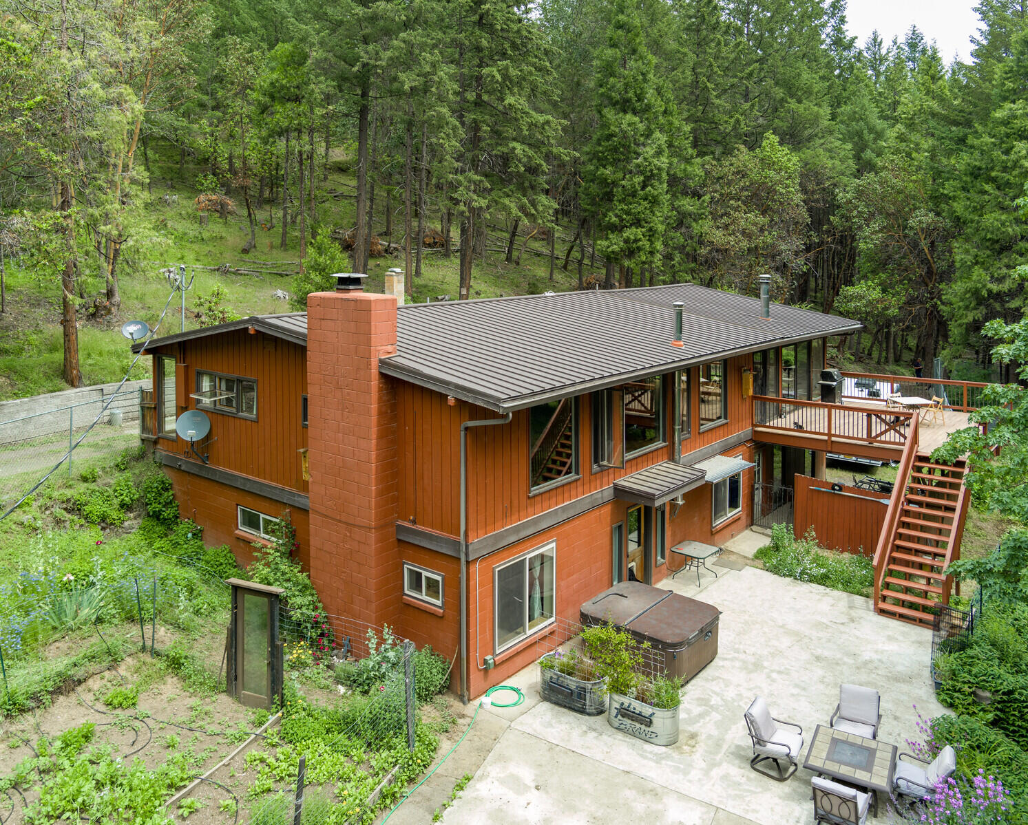 Take advantage of country living with the convenience of being close to town. This sunny home on 4+ acres is just an 8 minute drive to downtown Talent and a 15 minute drive to Ashland. The main level offers an excess of oversized windows framing the rich forest around the home. Enjoy the large kitchen along with an open concept dining and living room with a cozy fireplace. A flexible bonus room, sunroom, half bath and a large deck round out the top floor. The primary bedroom and two additional bedrooms are downstairs. The primary bath is beautifully remodeled and includes a deep tub, custom tile surround and heated slate floors. With .4 acres of water rights from Anderson Creek, there is plenty of water to irrigate and expand the fenced and deer proof yard. Most of the property is securely fenced and is a perfect setup for your dream hobby farm. There's an oversized two-car garage with tons of additional storage, RV parking, a huge wood shed, and a circular driveway for easy access.