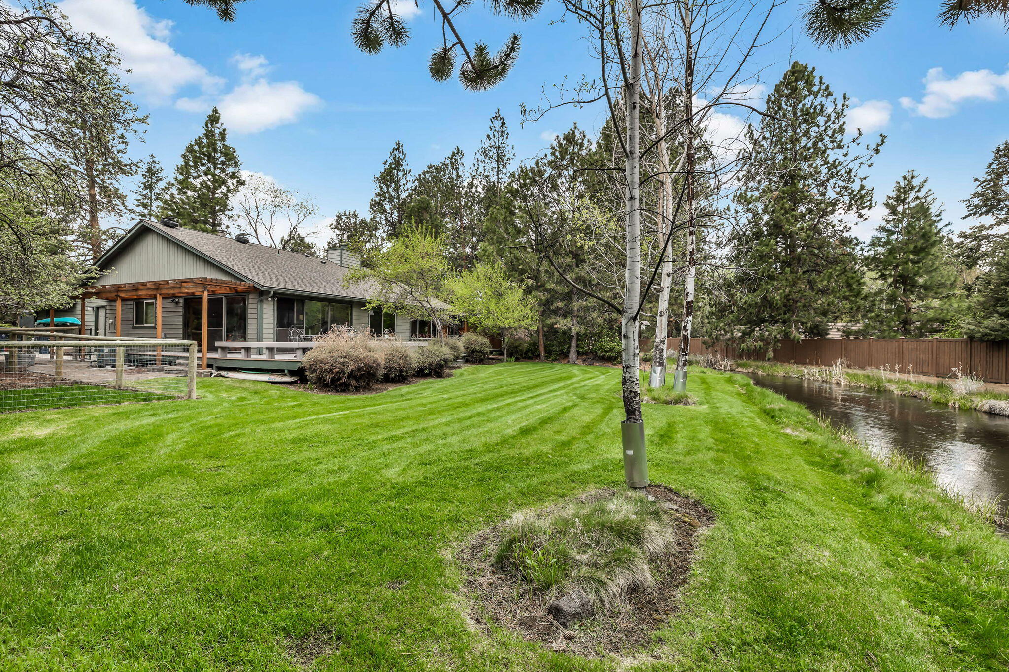 Enjoy Old Bend Living along the peaceful canal in coveted Woodside Ranch! This home drips with enough retro flavor to make style gurus salivate! With vaulted wood panel ceilings, leaded glass windows, red brick fireplace surround and an enclosed and conditioned sunroom you'll have just the right amount of charm and character to make this a very special home with your own finishing touches. With great bones and a new concrete septic tank installed in 2021 & new roof in 2020, the heavy lifting has been completed. A mix of tall Pines, Aspens and lush green manicured lawn create a serene PacNW paradise on an over ¾ acre lot. The large deck in the back yard looks over a flowing seasonal canal making this the perfect spot to enjoy summer. From this beautiful setting it's easy to forget you're still just a few minutes from all the fun in Downtown and down the street from new amenities like Caldera HS, Alpenglow Park, Larkspur Community Center and Cascade Lakes Brewing.