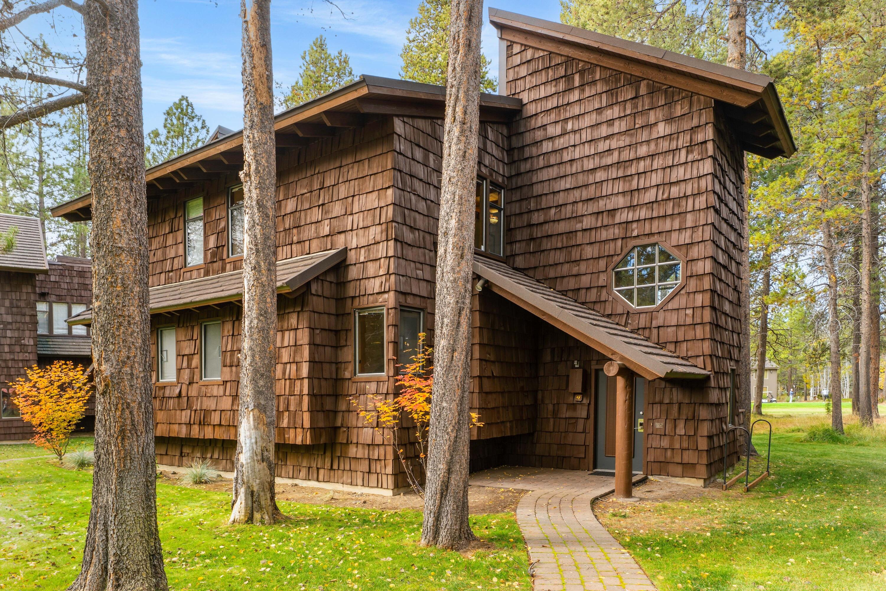 Location is everything! Lovingly owned by the same family for generations, this special retreat is ready to be passed on to the next owner. #12 Wildflower offers the ultimate Sunriver experience—just moments from the Village & Sunriver Resort, with panoramic views of the Meadows Golf Course. This charming three-level lodge-style condo features 2 bdrms, 2 baths, & two stunning wood-burning stone fireplaces—one in the great room & another in the primary suite. The ground-level entry provides convenient storage. The mid-level hosts the primary suite with a private balcony overlooking the greens, plus a guest bedroom & adjacent full bath. The top floor showcases a great room, open kitchen & dining area that flow onto a view deck surrounded by pines and fairway vistas. Don't miss the rooftop getaway—an ideal perch for stargazing or soaking in the beauty. Recent updates include quartz countertops in the kitchen & baths & refreshed showers. Sold furnished, A/C and an established rental.