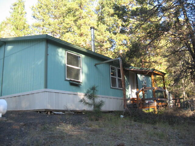 Great price on this nice little home on a cul-de-sac that backs up to mountainside with lots of trees for privacy! The lot backs up to privately owned Designated Forest Land. No need to worry about losing power due to the Generac Generator currently serviced and working. The interior needs a little TLC but not too much to pass this one by! The home features a split floor plan and open living room/kitchen area. The home has a beautiful metal roof and a great pumphouse. The exteriors of the home and pump house have been recently painted. There is an additional shed with lots of space for tools and equipment, and a small greenhouse/shed for those with a green thumb! The well, drilled in 1998, showed a 35 GPM flow at that time. Seller will provide a $5,000 flooring allowance!
